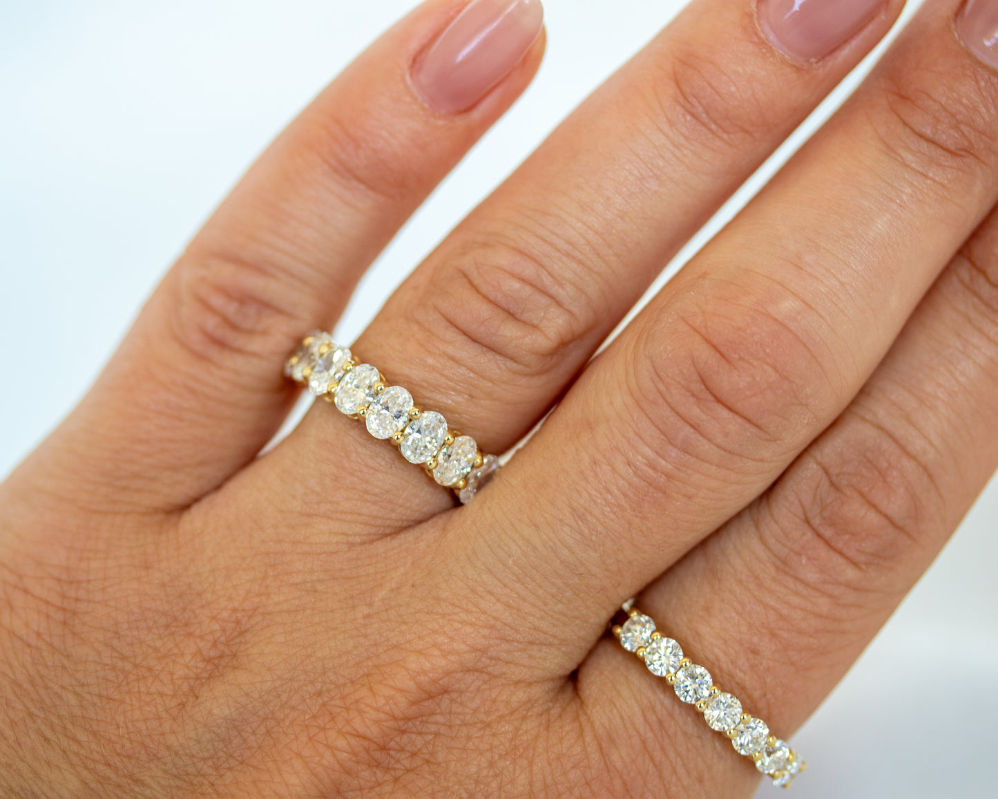 Oval-cut diamond eternity band worn stacked with a plain gold band