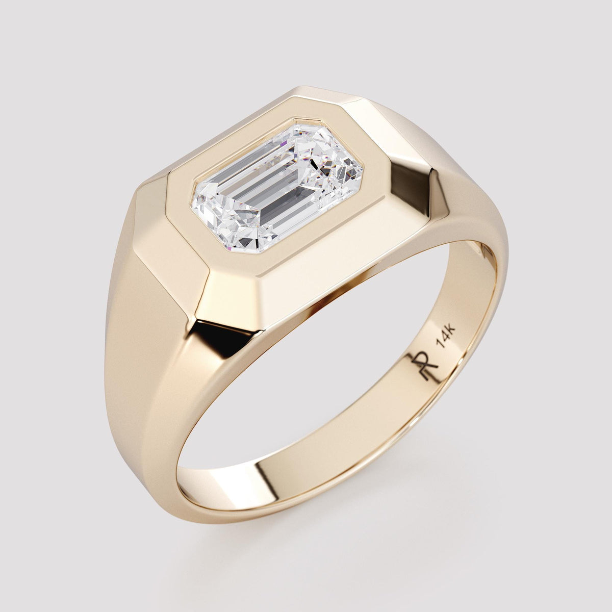 Yellow gold signet ring with an emerald-cut white diamond on a gray background