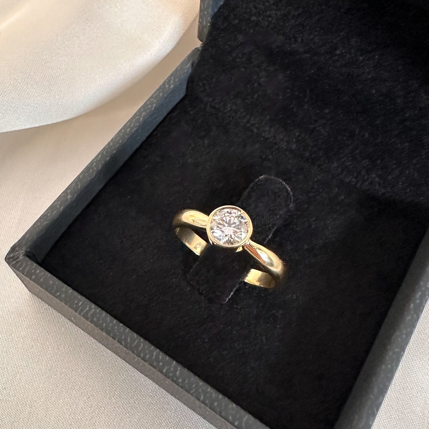 gold solitaire ring with bezel setting in black velvet box