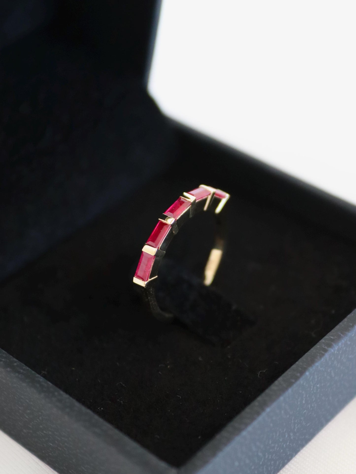 Gold ring with baguette rubies in a black box