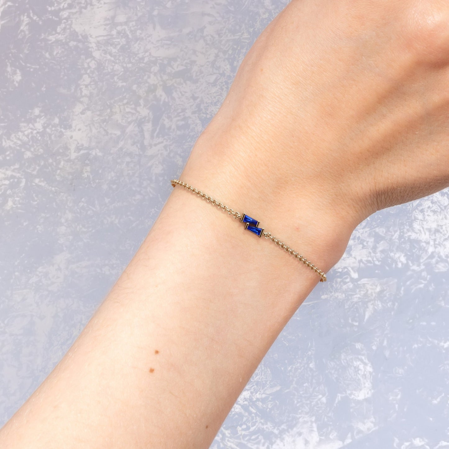 Blue sapphire baguette gold bracelet worn on the wrist