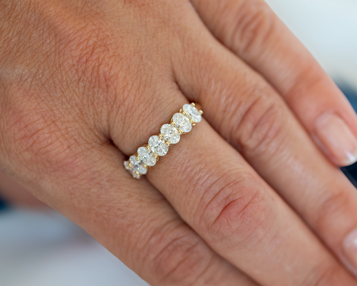 Close-up of the seven-stone oval-cut diamond ring worn on finger