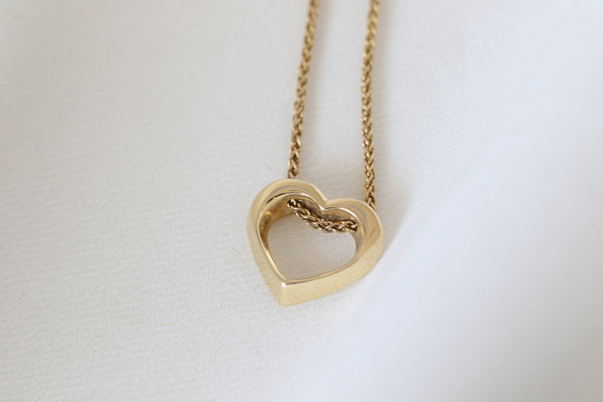 14K yellow gold twisted open heart necklace on a spiga chain, on a light background