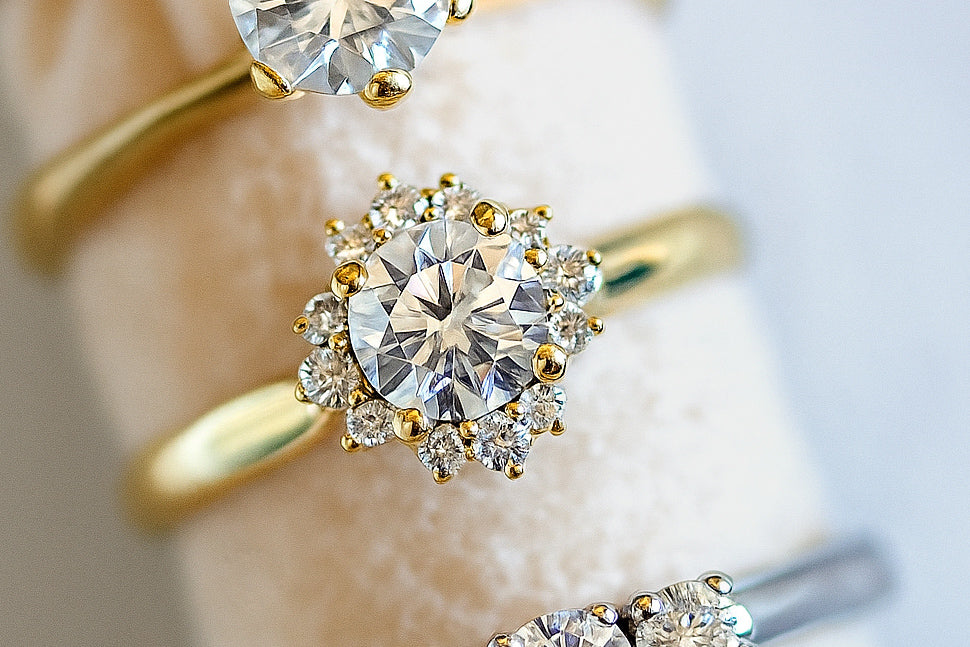 Close-up of elegant diamond engagement rings in yellow and white gold displayed on a soft velvet holder, showcasing different cuts and settings with bright sparkle — perfect visual for a lab-grown and natural diamond jewelry guide.