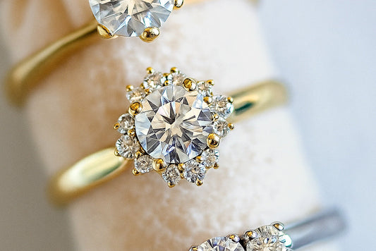 Close-up of elegant diamond engagement rings in yellow and white gold displayed on a soft velvet holder, showcasing different cuts and settings with bright sparkle — perfect visual for a lab-grown and natural diamond jewelry guide.