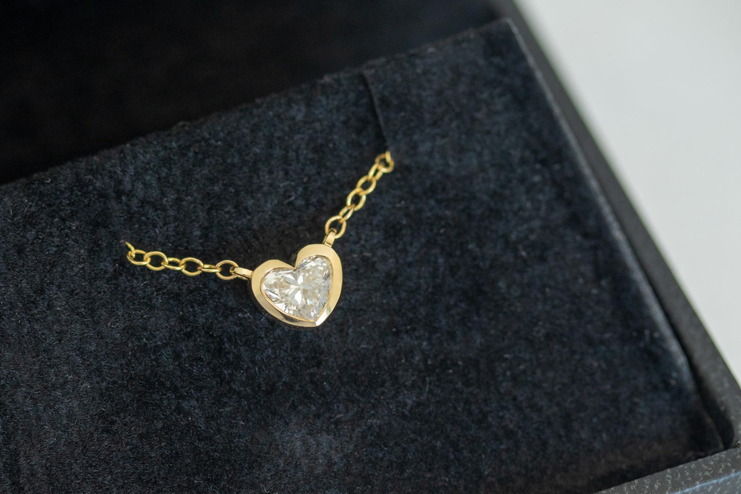 Gold heart-shaped necklace on a dark fabric surface