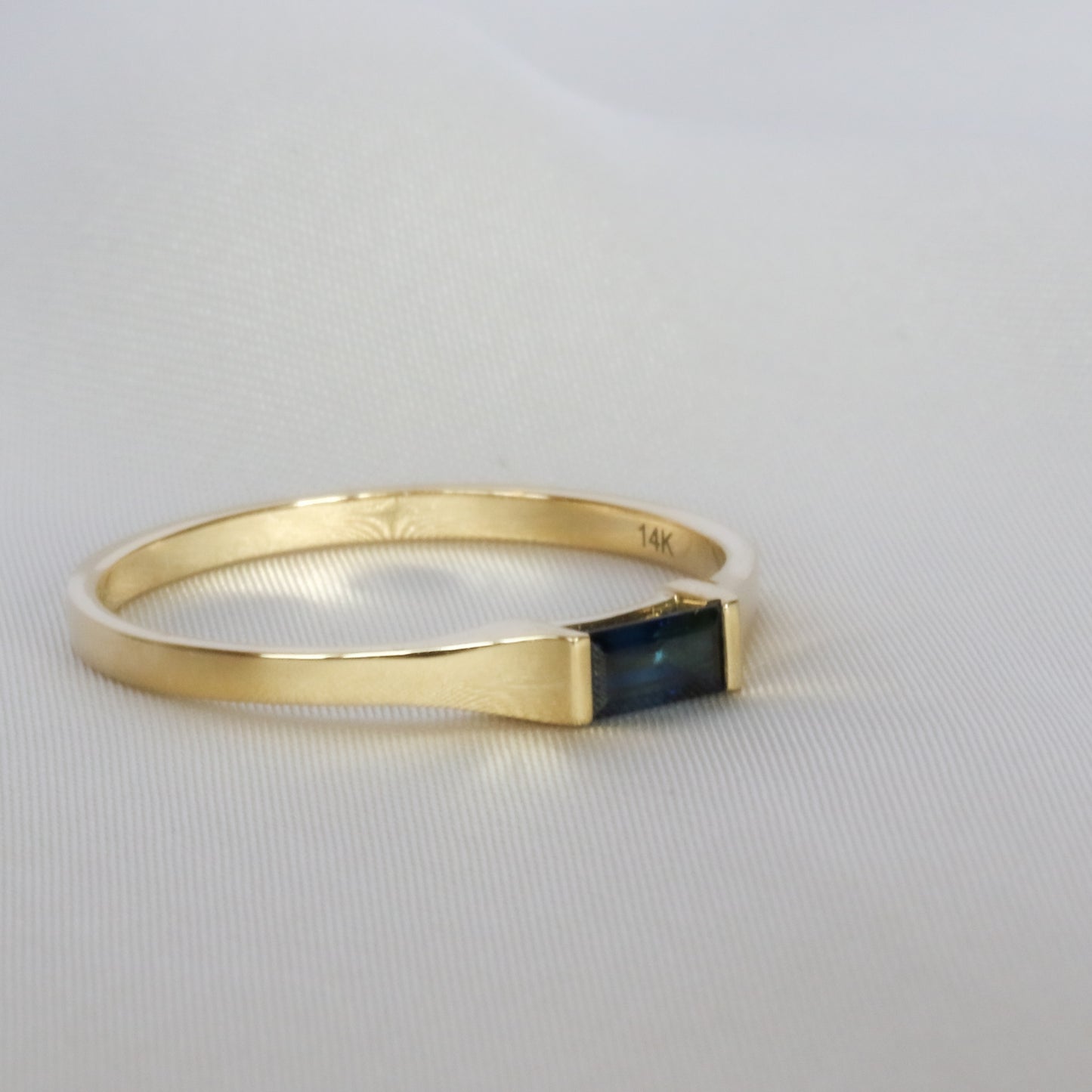 blue sapphire baguette ring in off side on off white cloth