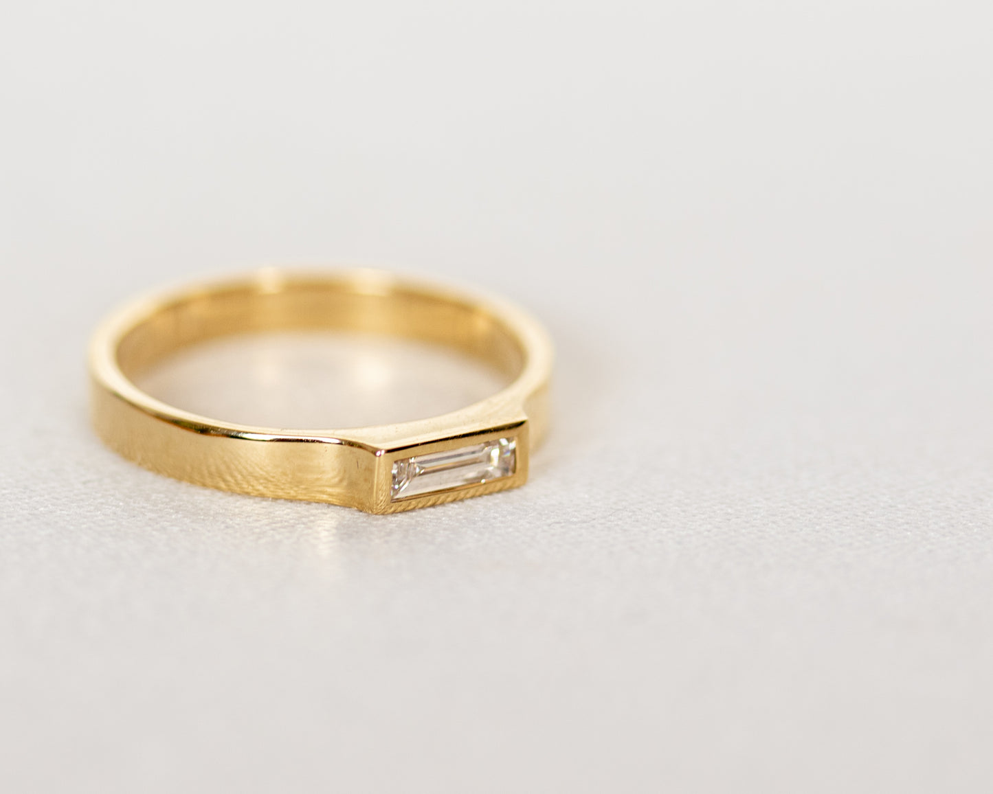 Close-up of baguette diamond in full bezel setting, 14K gold ring