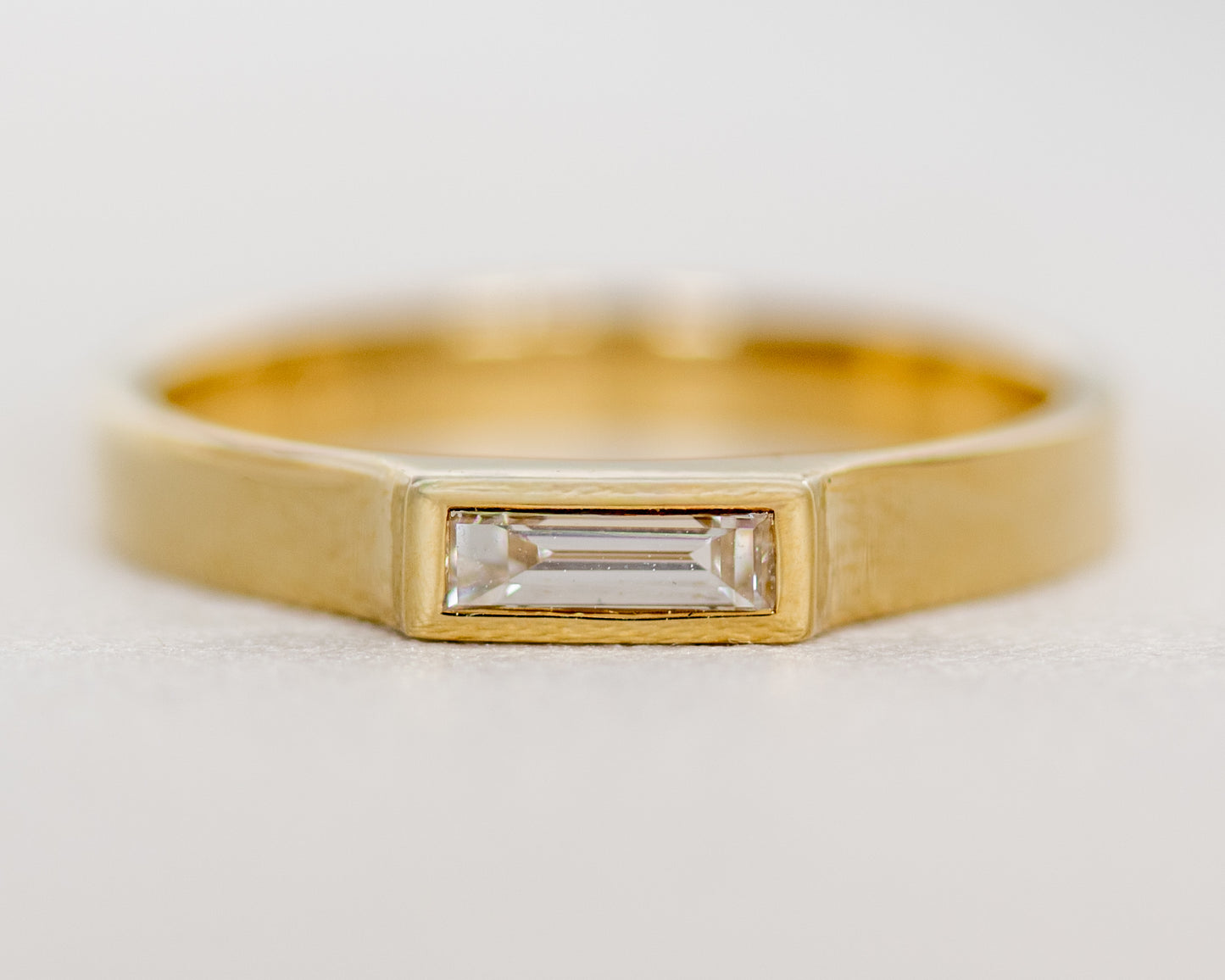 Front view of 14K gold baguette diamond ring with full bezel setting