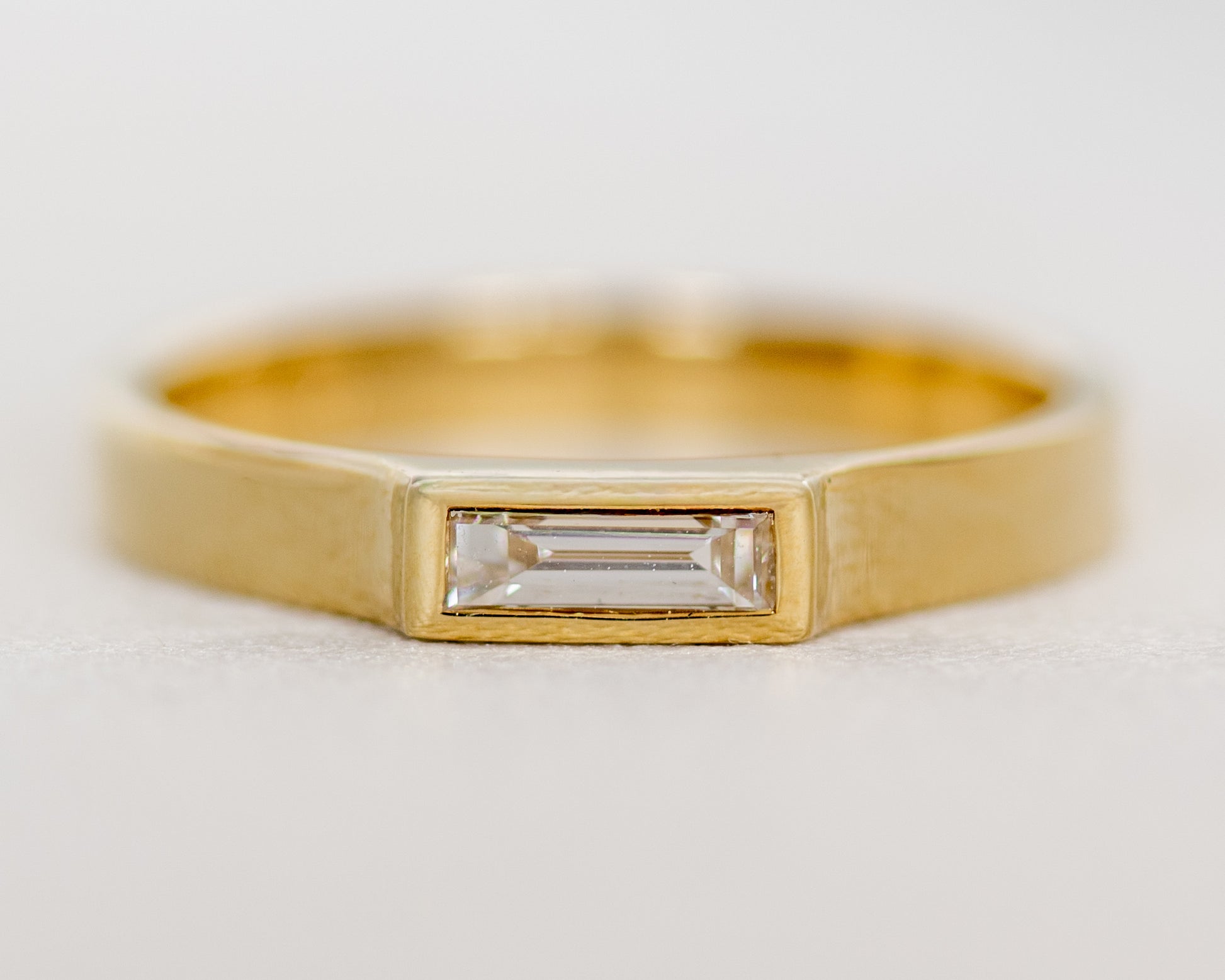 Front view of 14K gold baguette diamond ring with full bezel setting