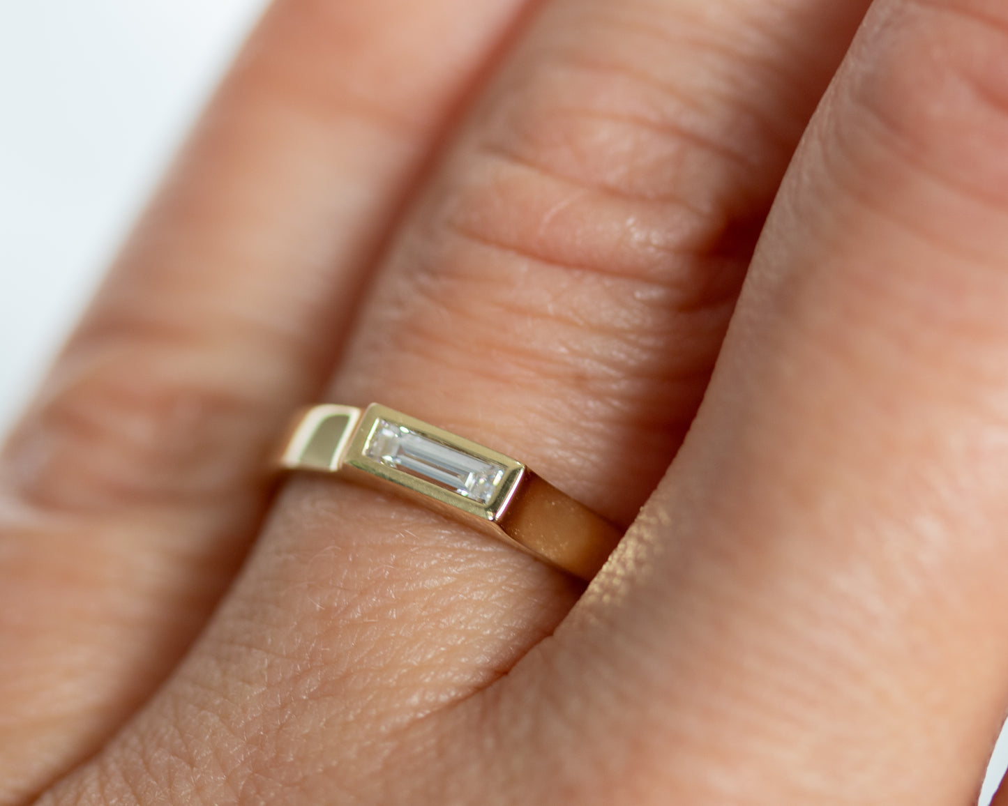 Close-up of 14K gold baguette diamond ring worn on hand