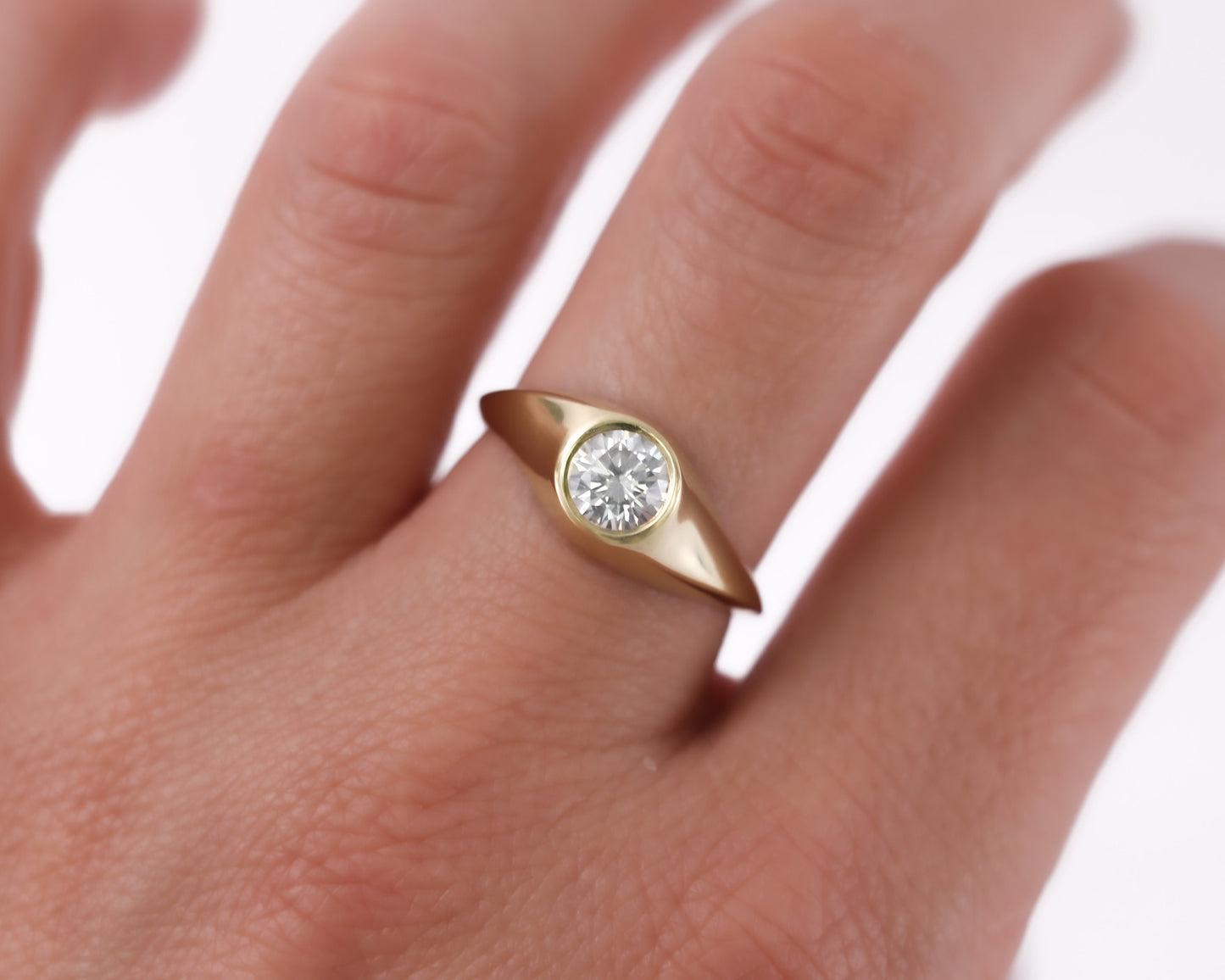 14K gold diamond signet ring shown on hand, minimalist handcrafted fine jewelry with round brilliant-cut stone and smooth polished finish.