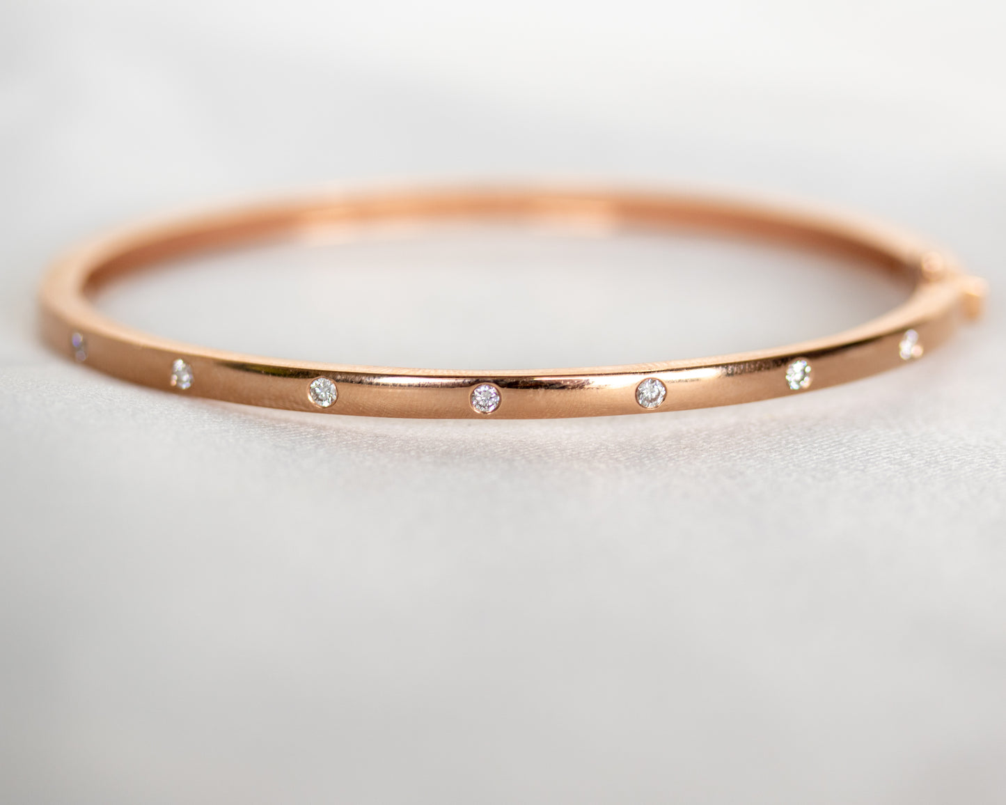 14K gold bangle with seven flush-set round diamonds, front view