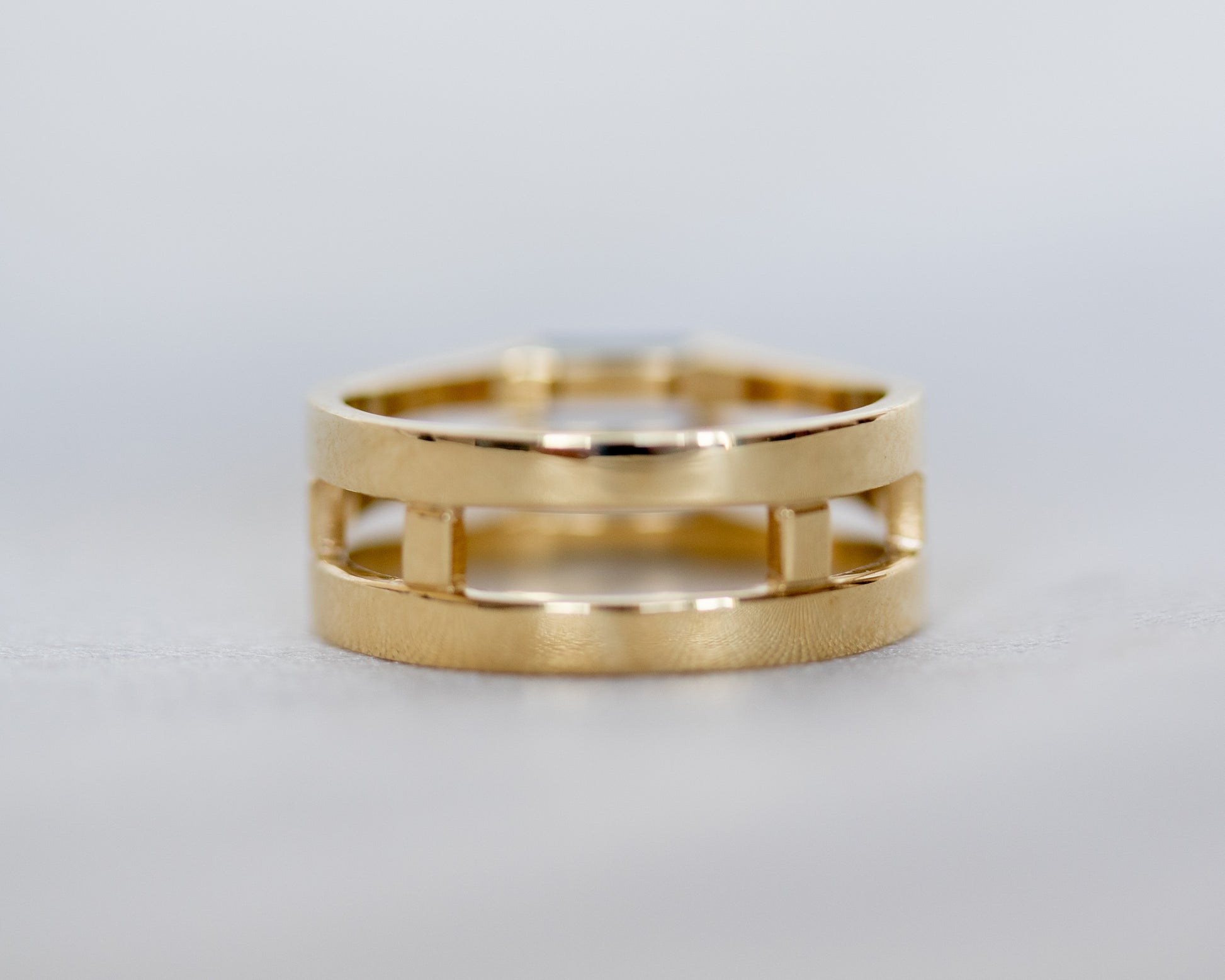 Gold ring with a geometric design on a light gray background