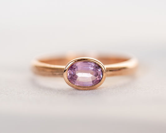 Front view of 14K gold oval pink sapphire ring with full bezel setting
