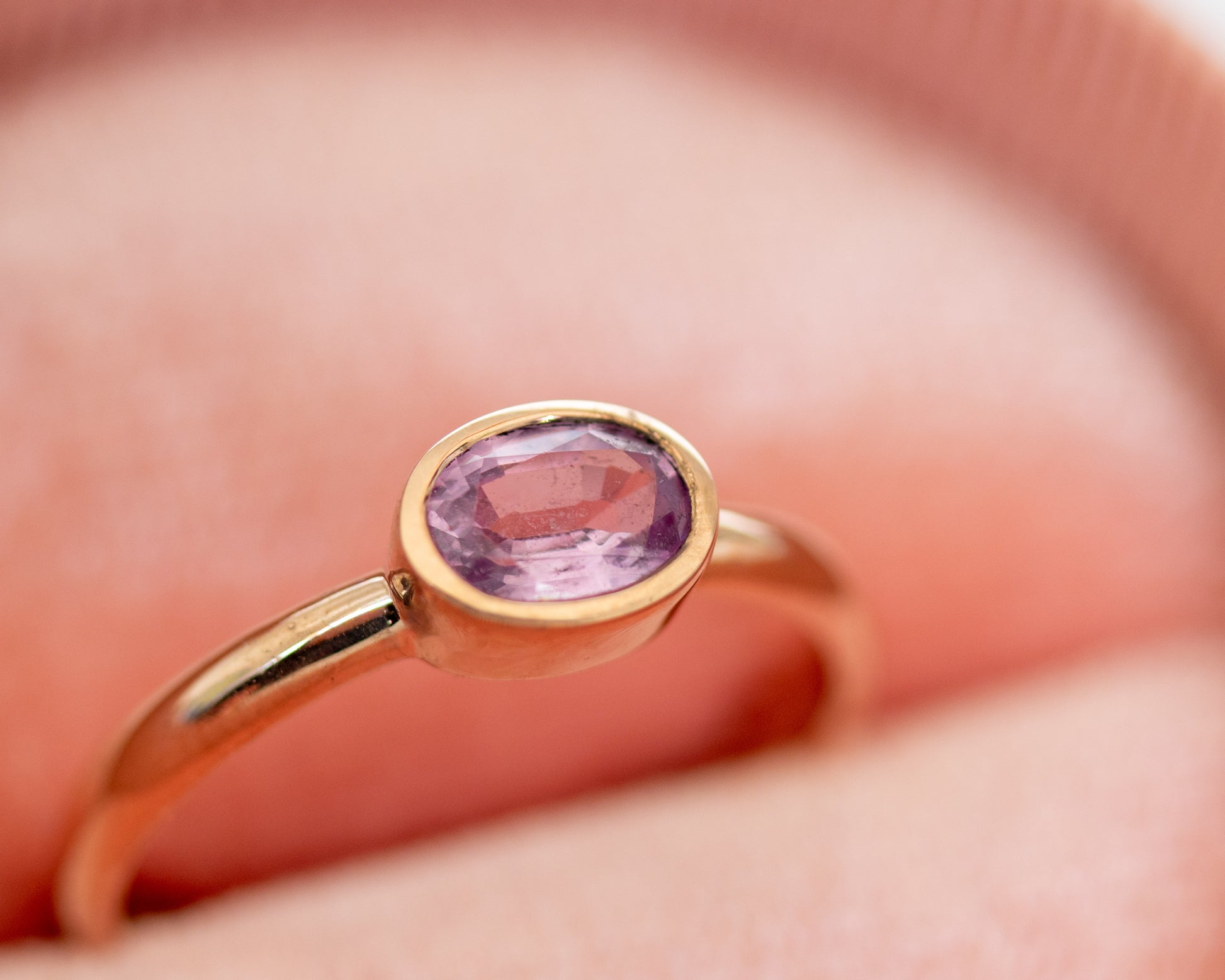 14K gold pink sapphire bezel-set ring displayed in jewelry box