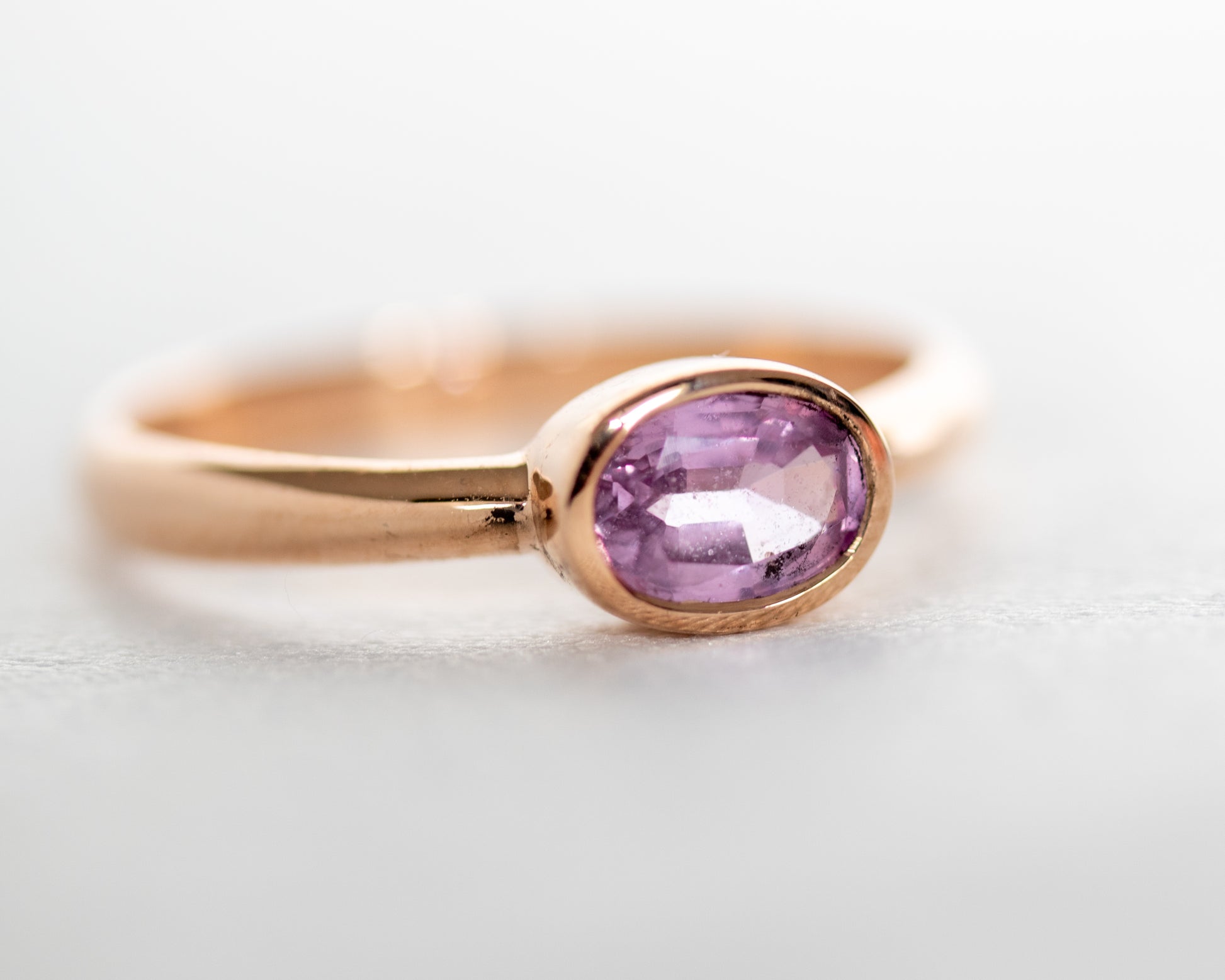 Side view of 14K rose gold pink sapphire bezel-set solitaire ring