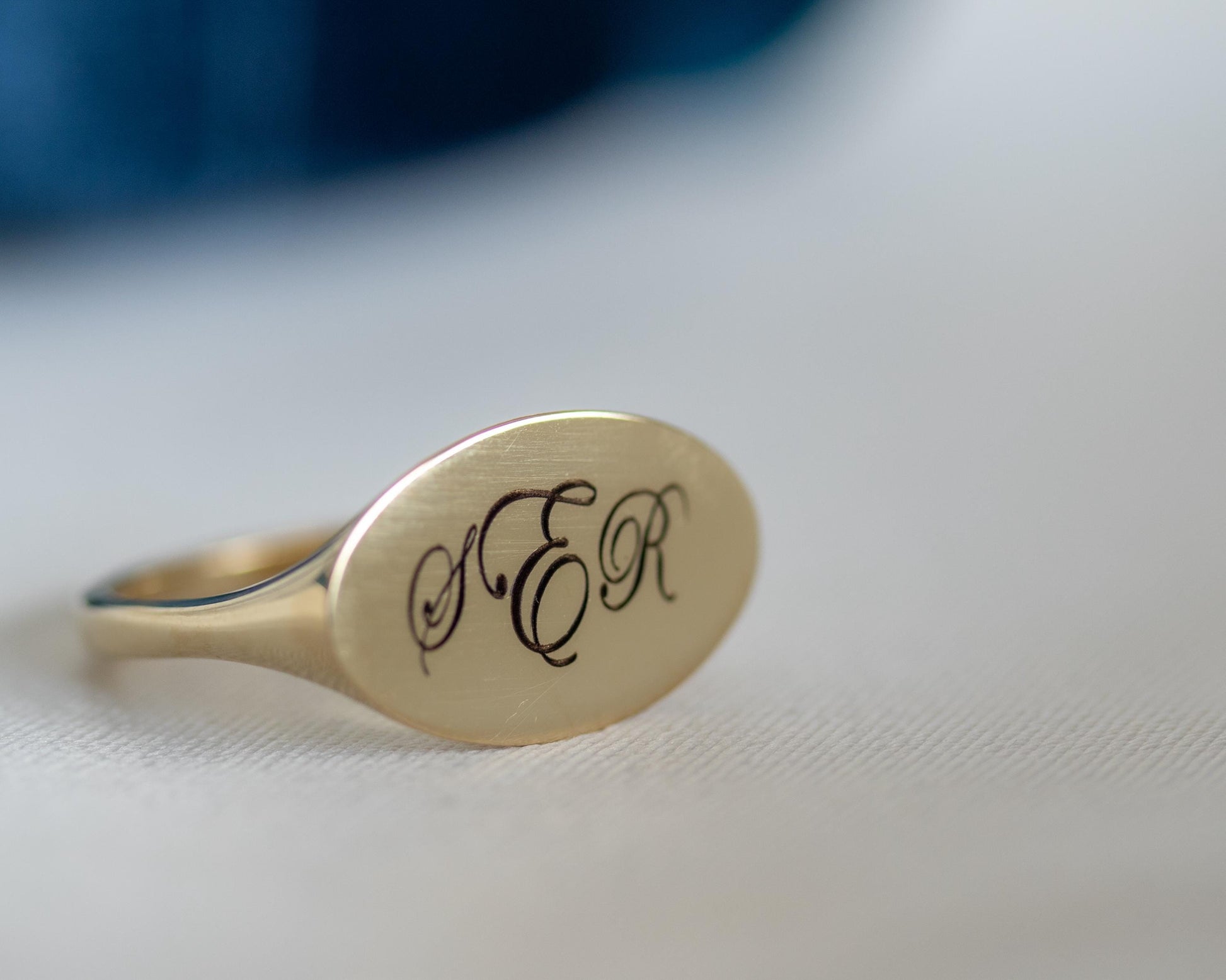 Gold ring with 'S E R' engraving on a white surface