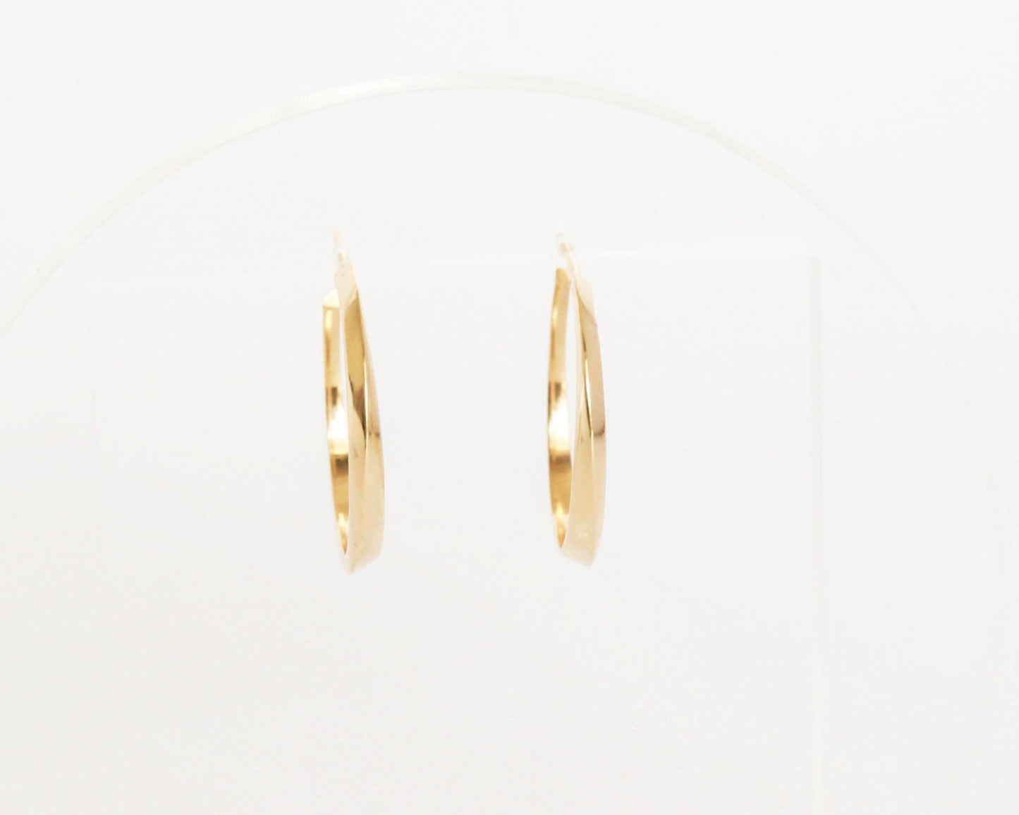 Front view of 14K gold twist hoop earrings with geometric sculpted design, modern fine jewelry photographed on white display background.