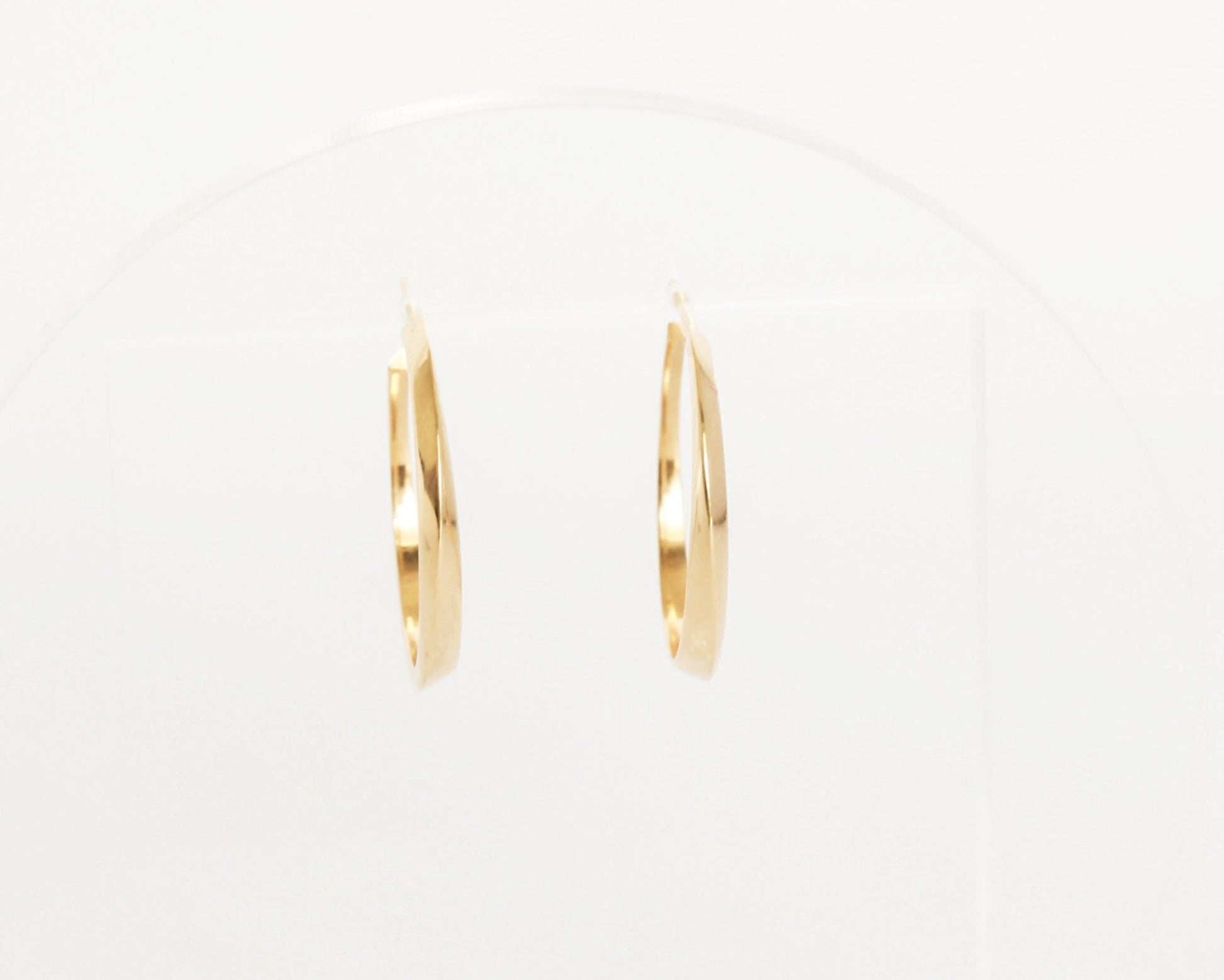 Front view of 14K gold twist hoop earrings with geometric sculpted design, modern fine jewelry photographed on white display background.