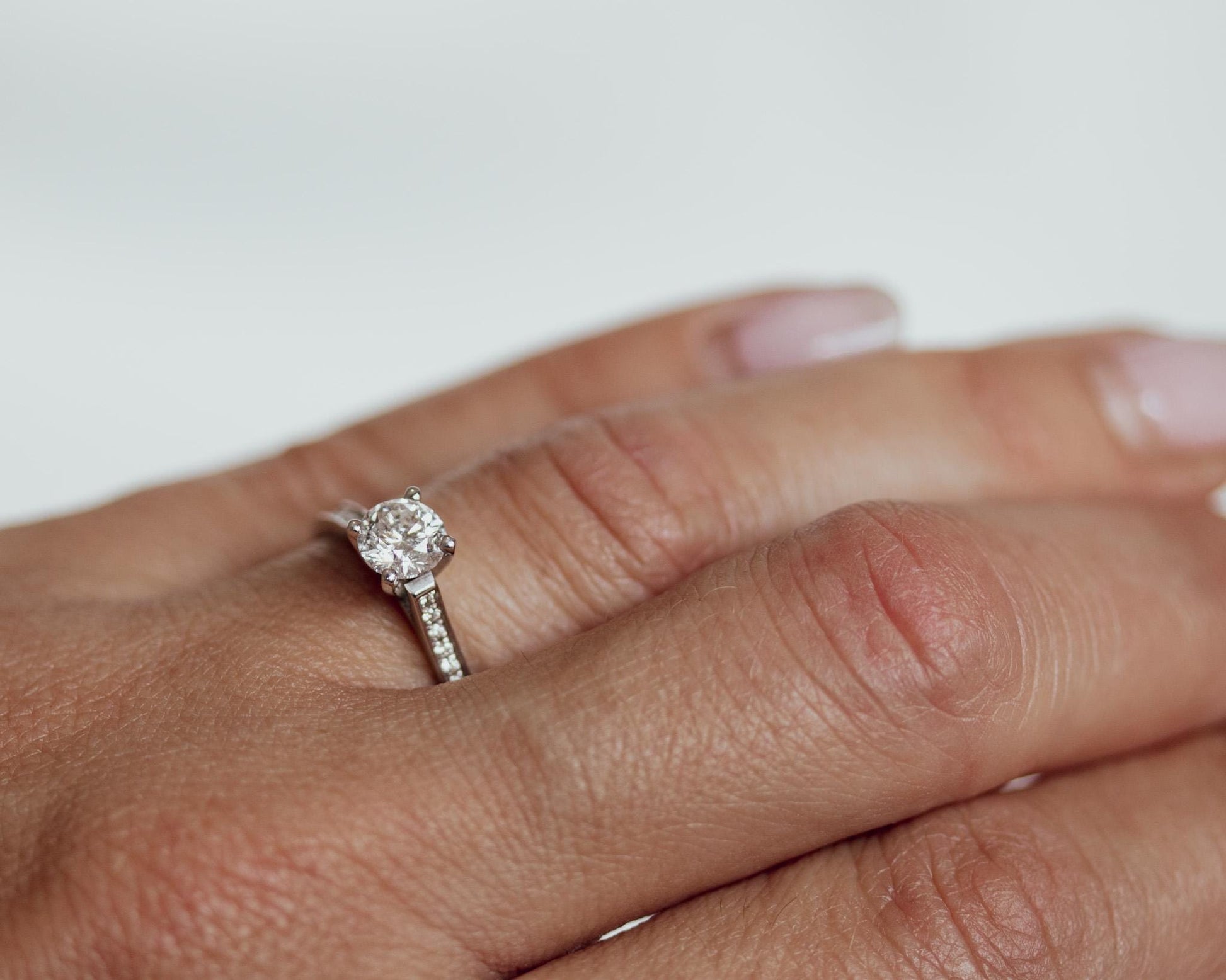 14K white gold engagement ring with round diamond and pavé band, shown on hand for natural fit and sparkle
