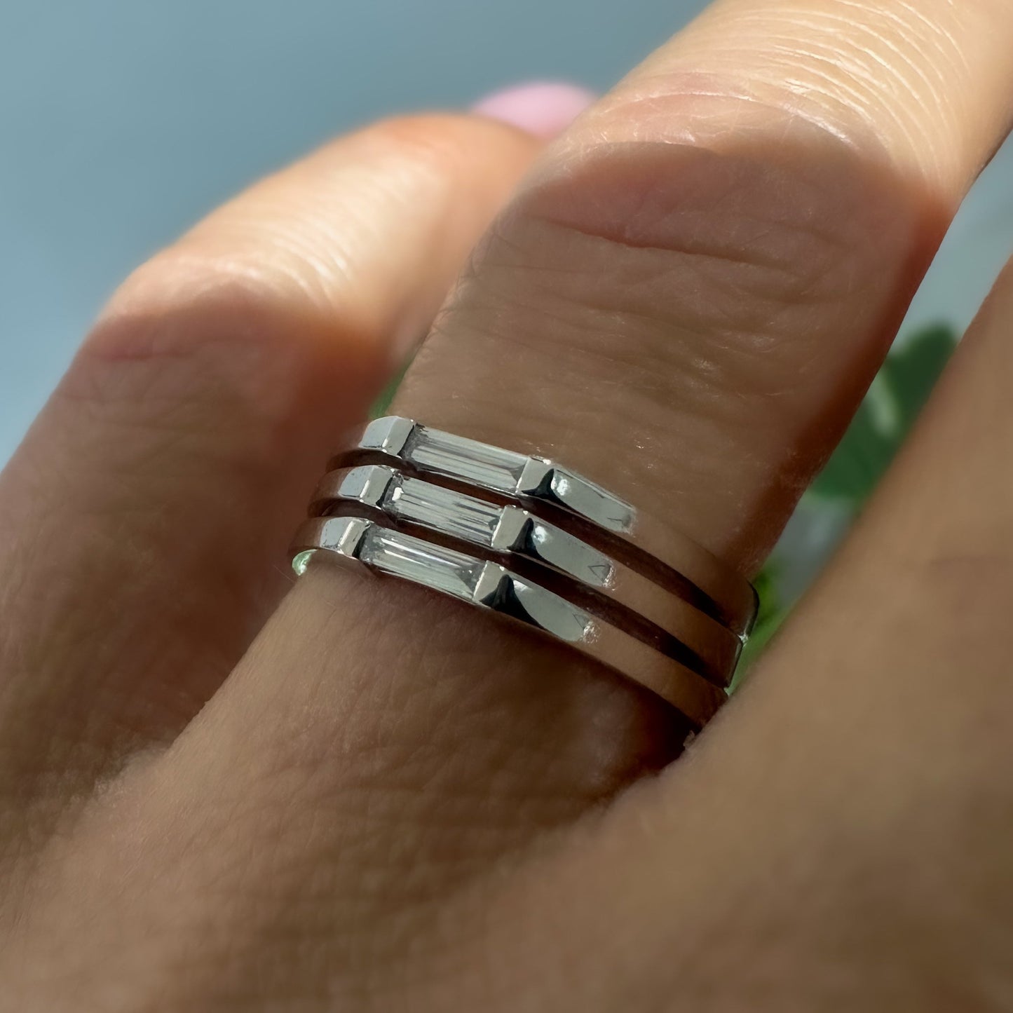 A minimalist ring design with a stack of needle baguette cut sapphires, set in a 14K gold band, on a women's hand