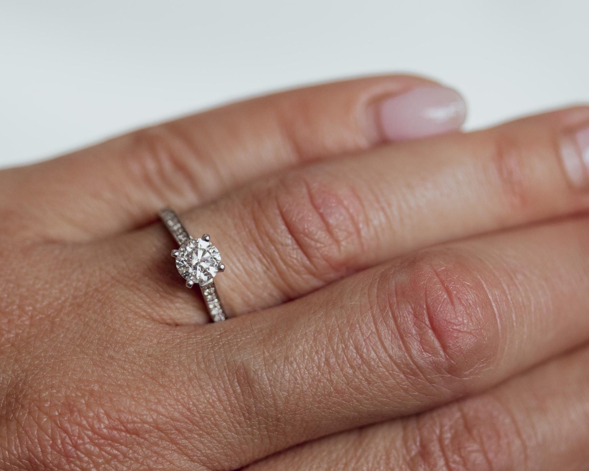 14K white gold round diamond engagement ring with pavé band, shown on hand for realistic sparkle and elegant fit