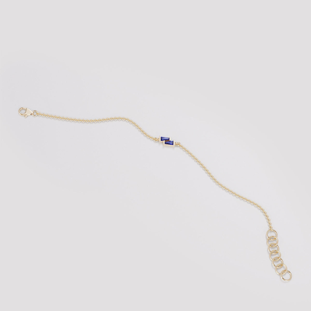 Rendering of an asymmetric blue sapphire baguette bracelet in yellow gold at full length