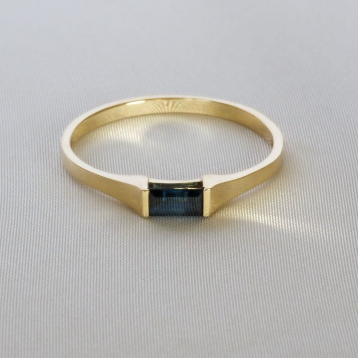Baguette blue sapphire gold ring on off-white cloth