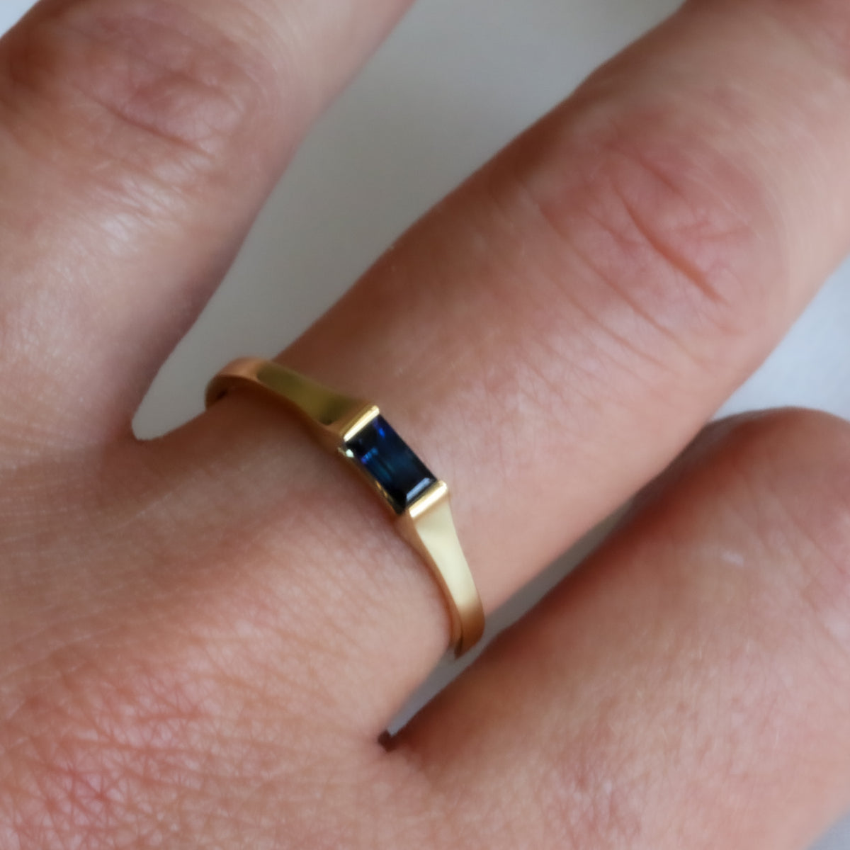 Baguette blue sapphire ring in yellow gold worn on the hand