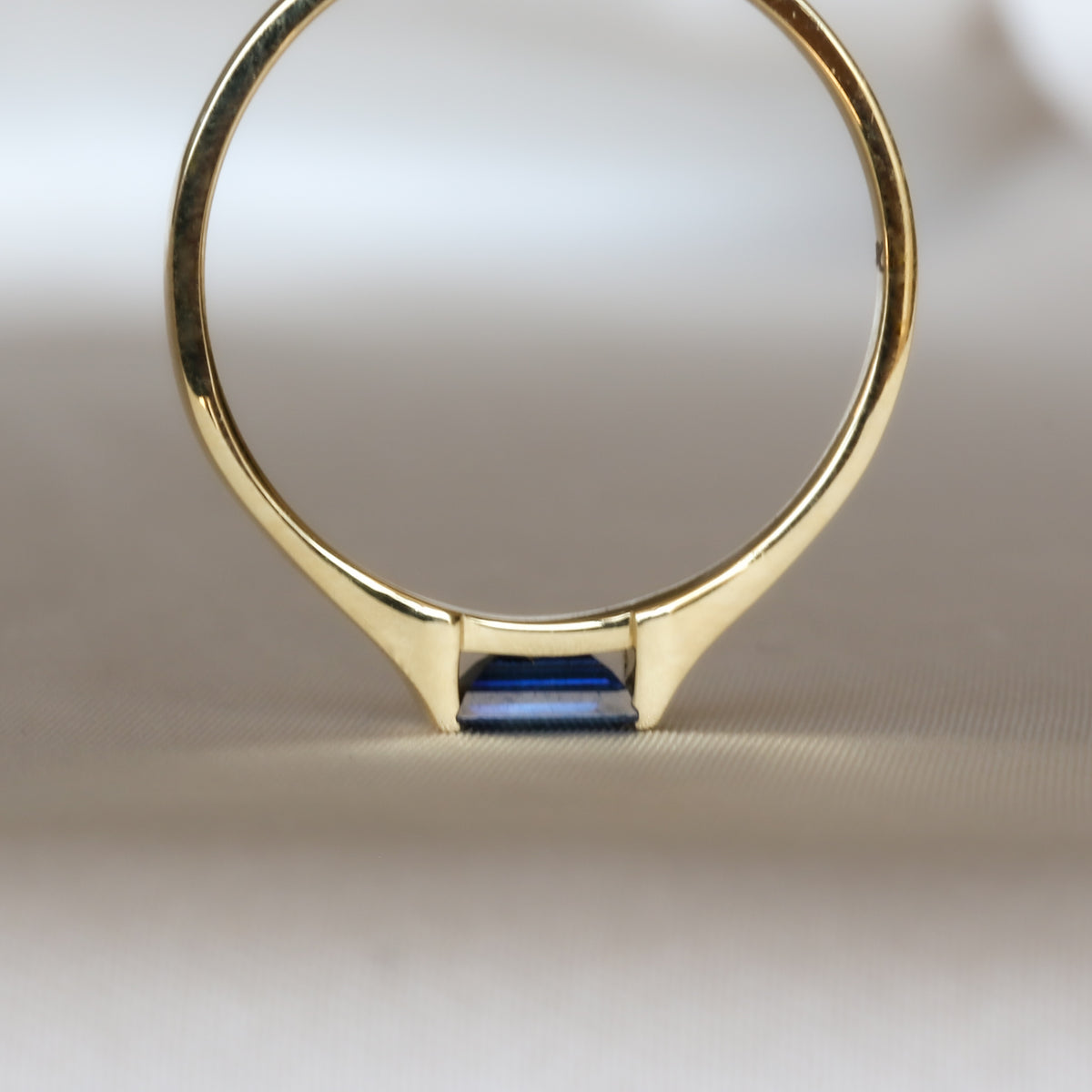 Baguette blue sapphire gold ring standing on a stone surface