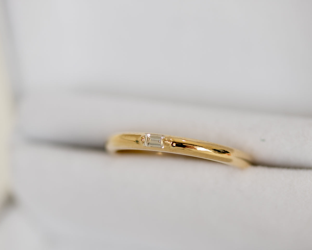 Yellow gold baguette diamond band in a gray velvet ring box