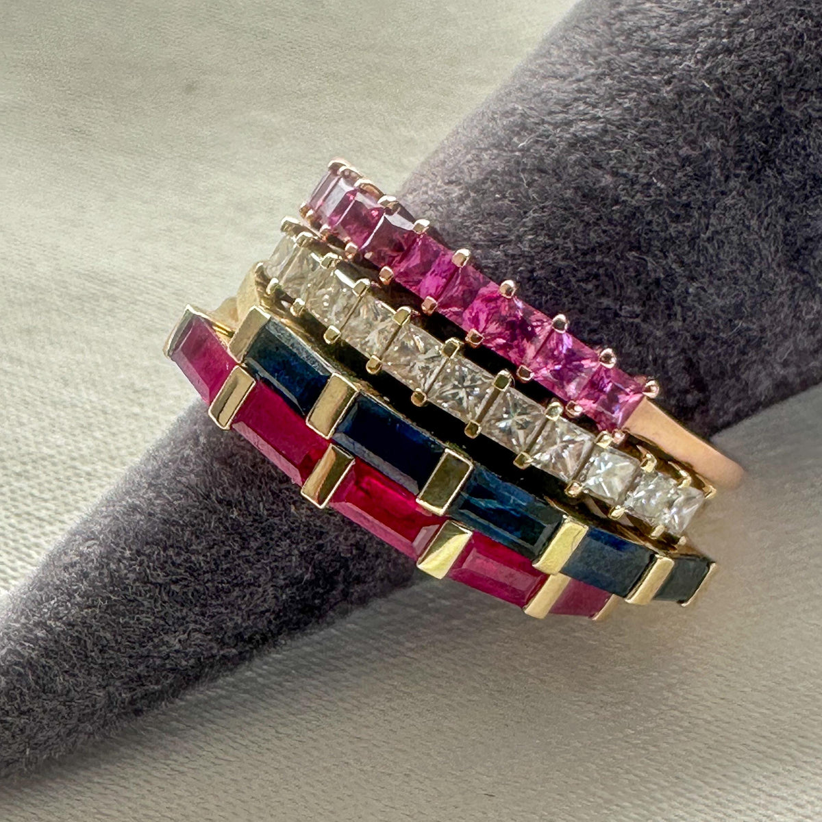 Stack of 14K gold baguette bands with blue sapphires, rubies, pink sapphires and diamonds