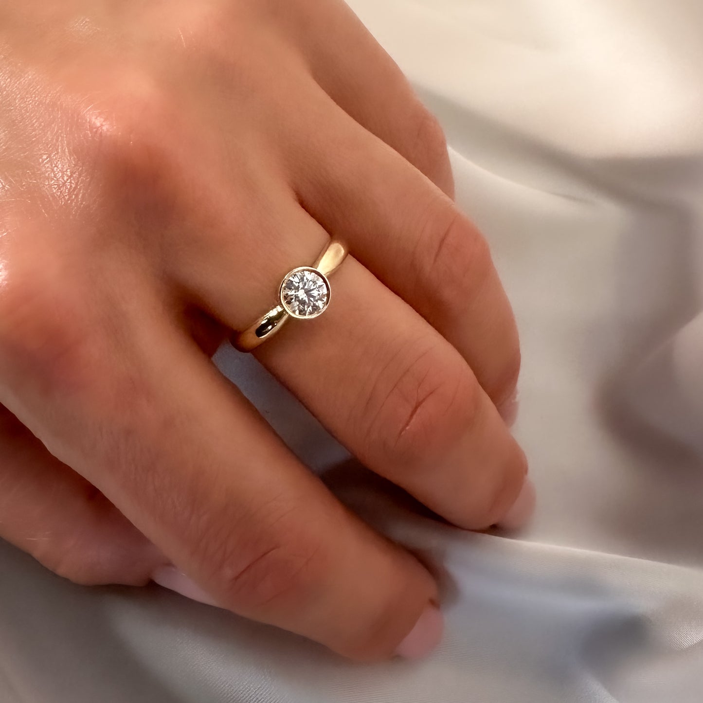 gold solitaire ring with bezel setting on hand
