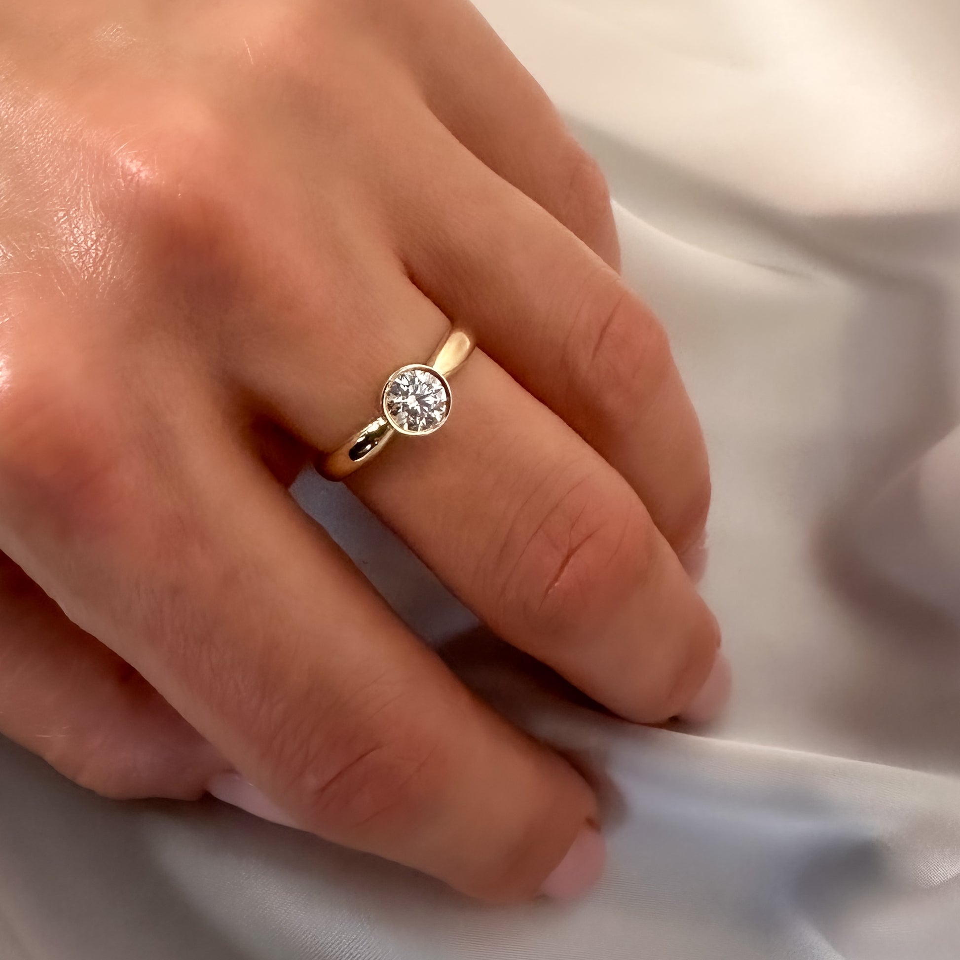 gold solitaire ring with bezel setting on hand