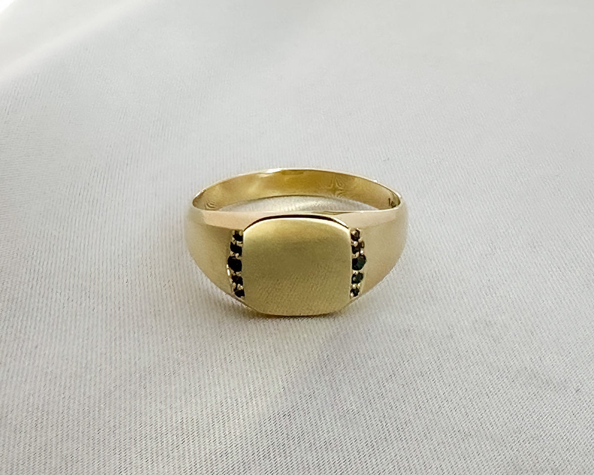 Close-up of flush-set black diamonds on a yellow gold signet ring