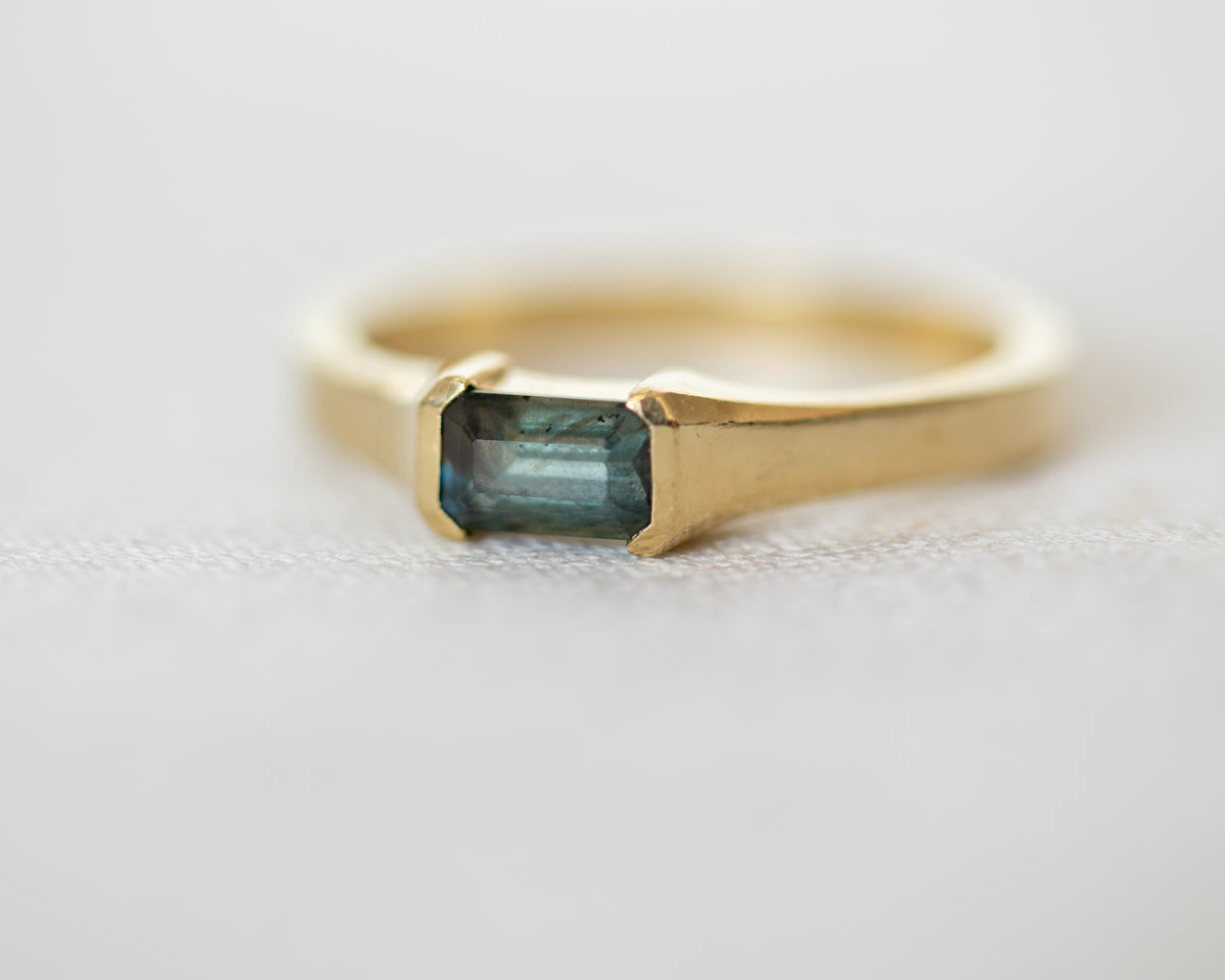 Blue-gray sapphire in a half bezel setting, 14K yellow gold ring, close-up