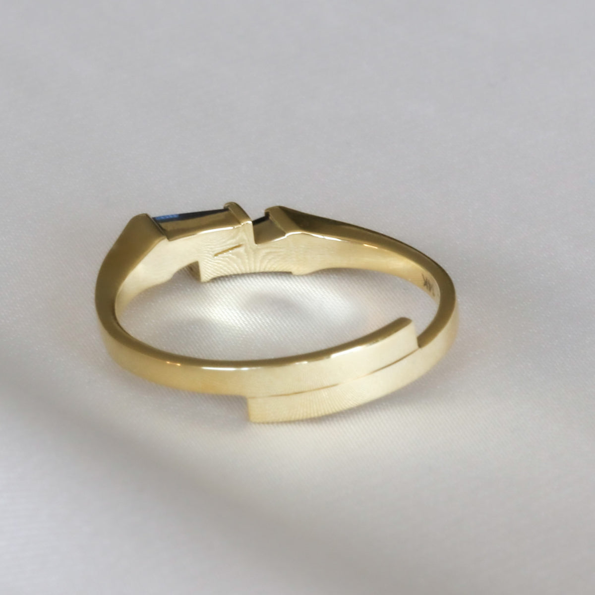 Side view of a 14K yellow gold ring with two tapered baguette blue sapphires in a bar setting