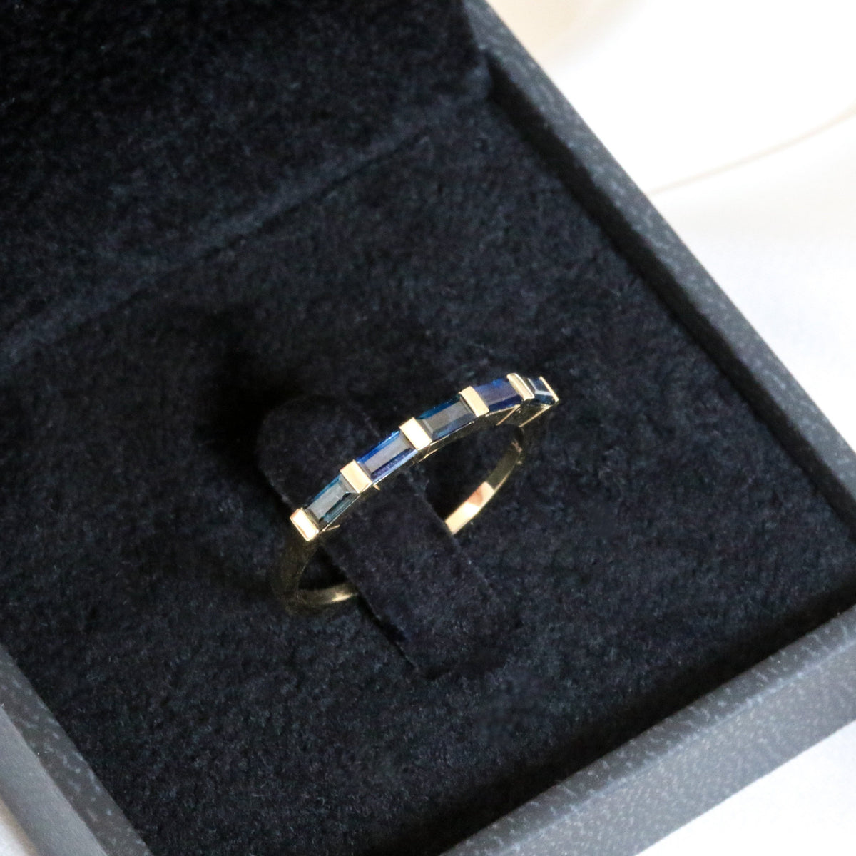 Blue sapphire five-stone band in 14K gold in an open black velvet box