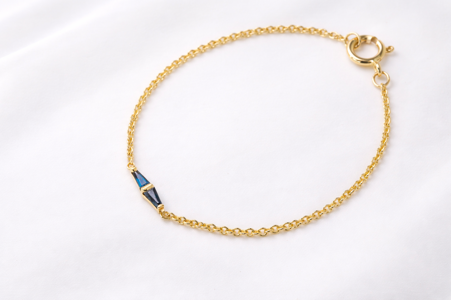 Minimal 14K gold bracelet with a geometric blue sapphire centerpiece on a fine gold chain