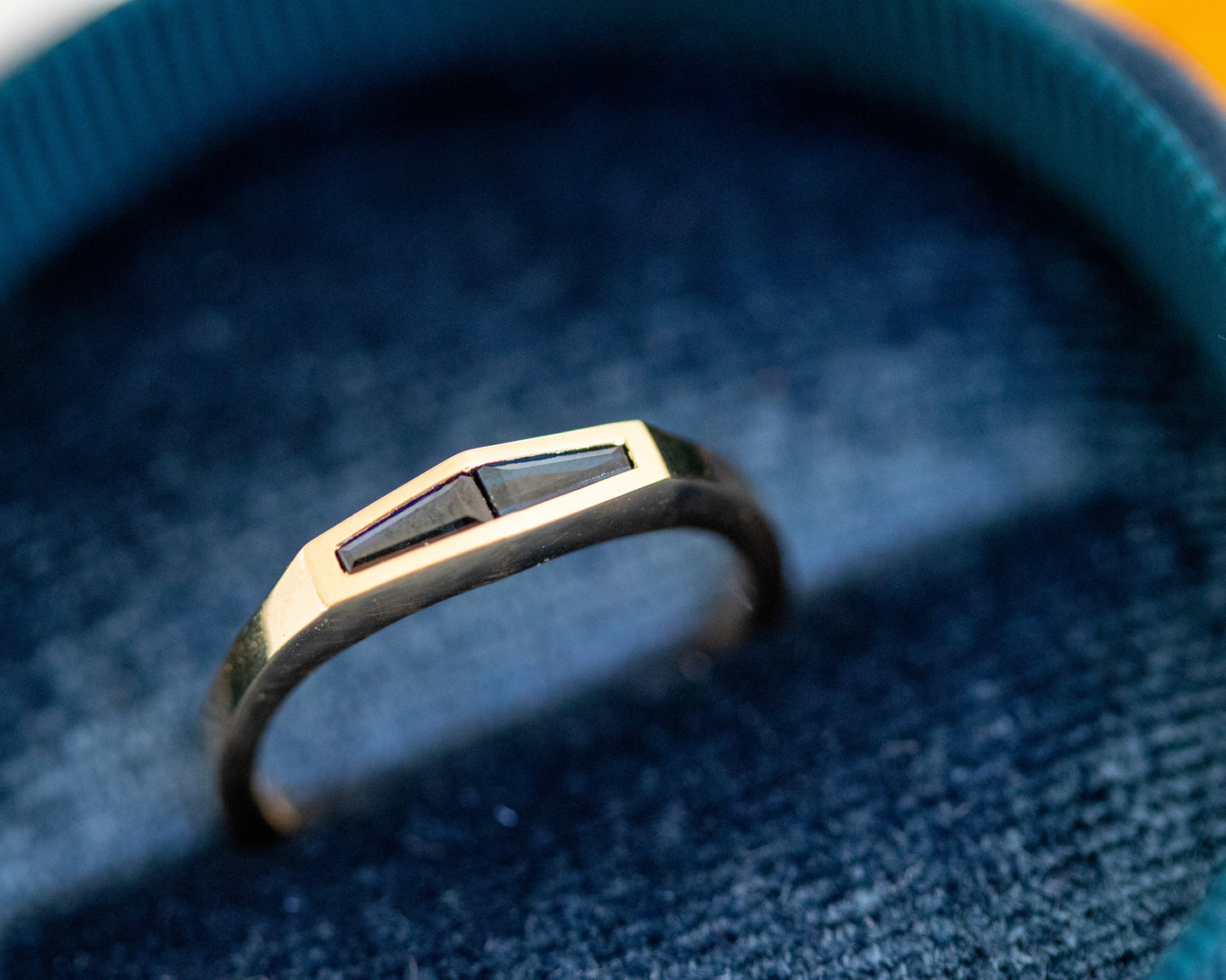 Tapered baguette blue sapphire ring in 14K yellow gold, presented in a velvet ring box.