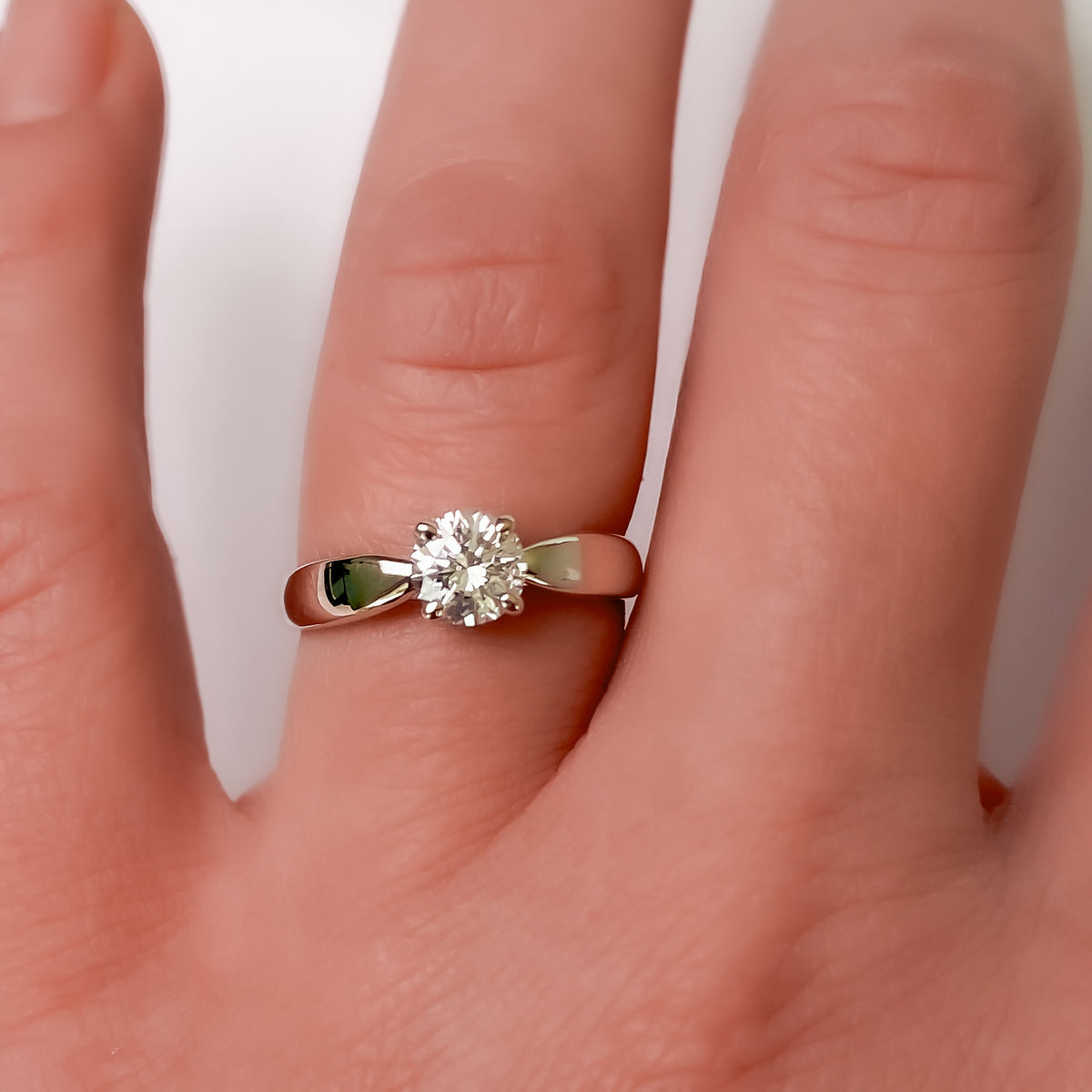 Round diamond cathedral solitaire ring in white gold worn on the finger
