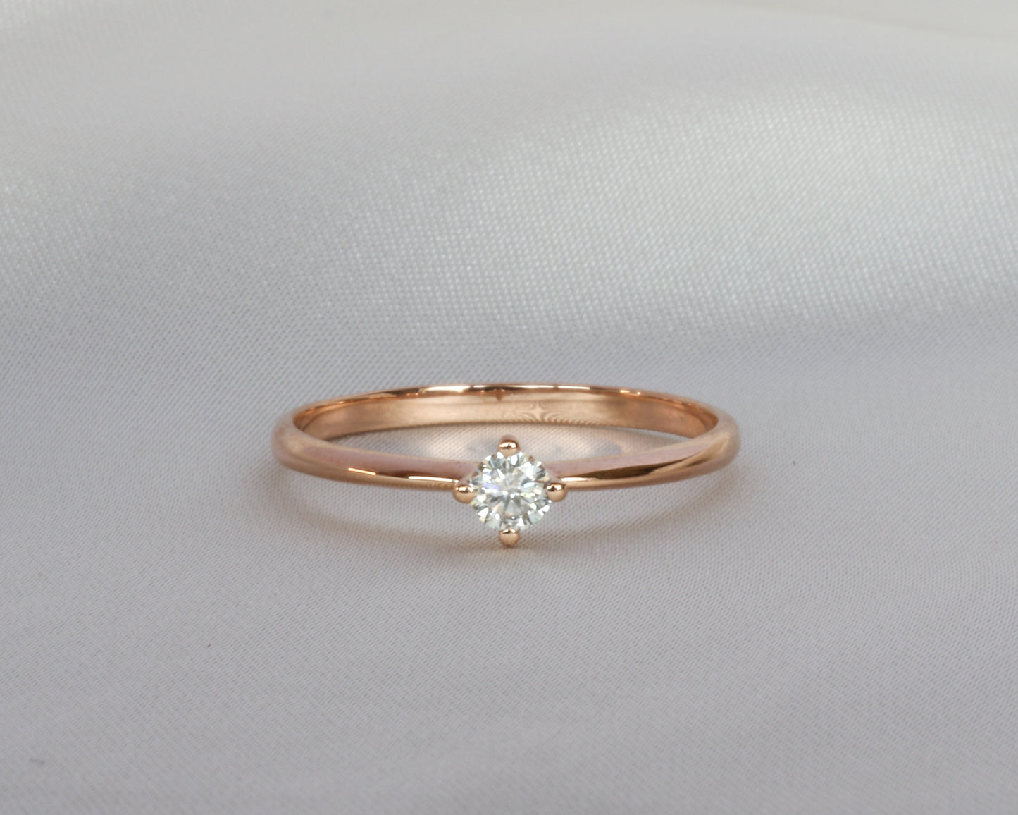 Rose gold ring with a diamond on a light gray background