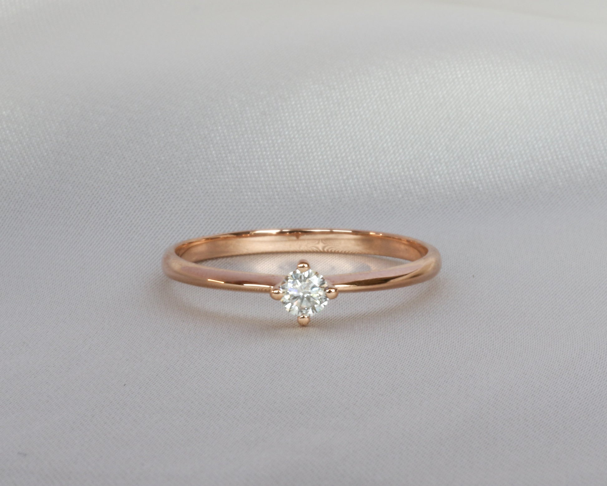 Rose gold ring with a diamond on a light gray background
