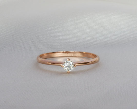 Rose gold ring with a diamond on a light gray background