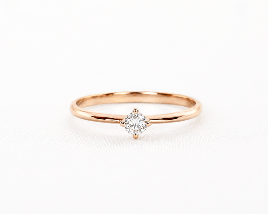 Rose gold ring with a diamond on a light gray background
