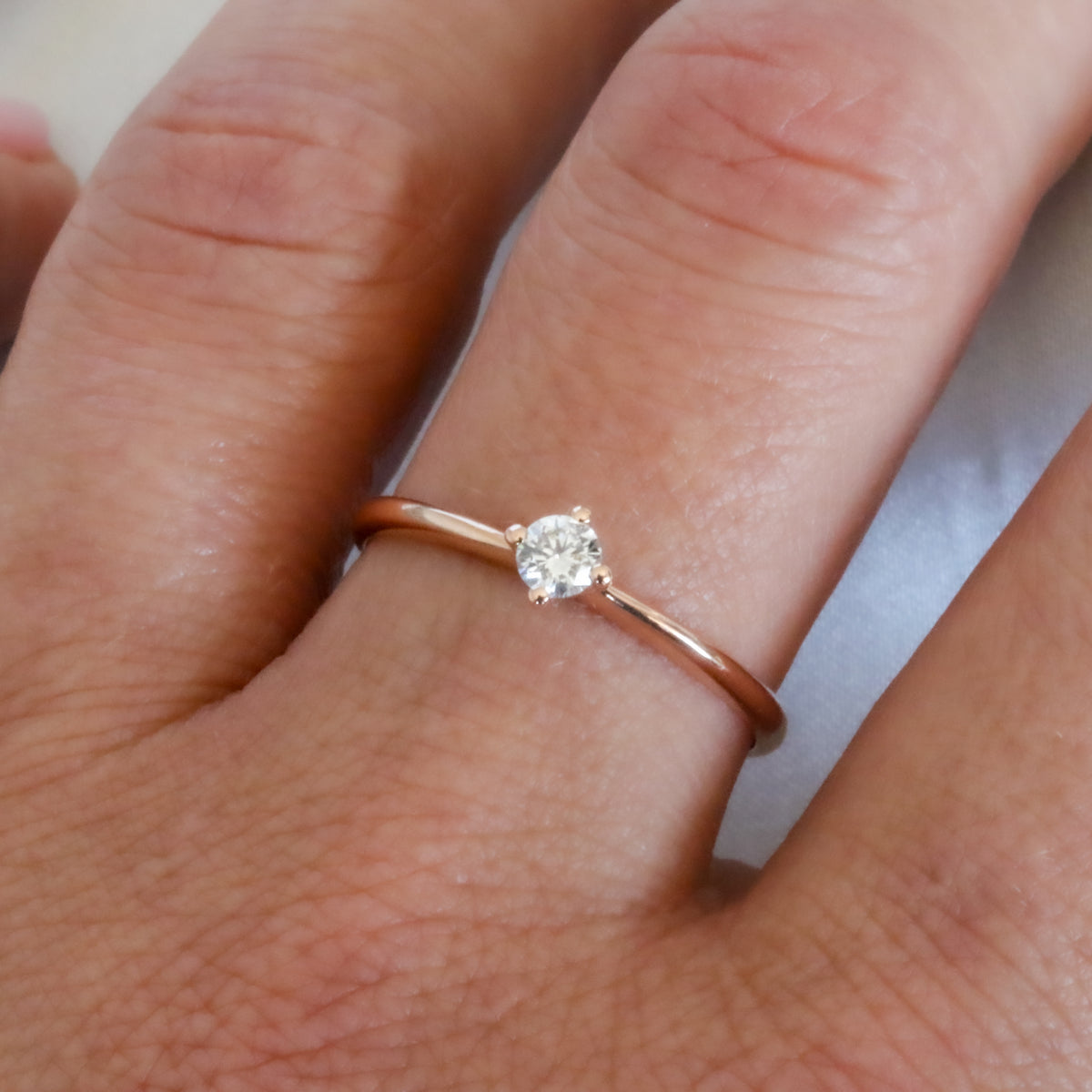 Dainty rose gold diamond solitaire ring worn on the finger