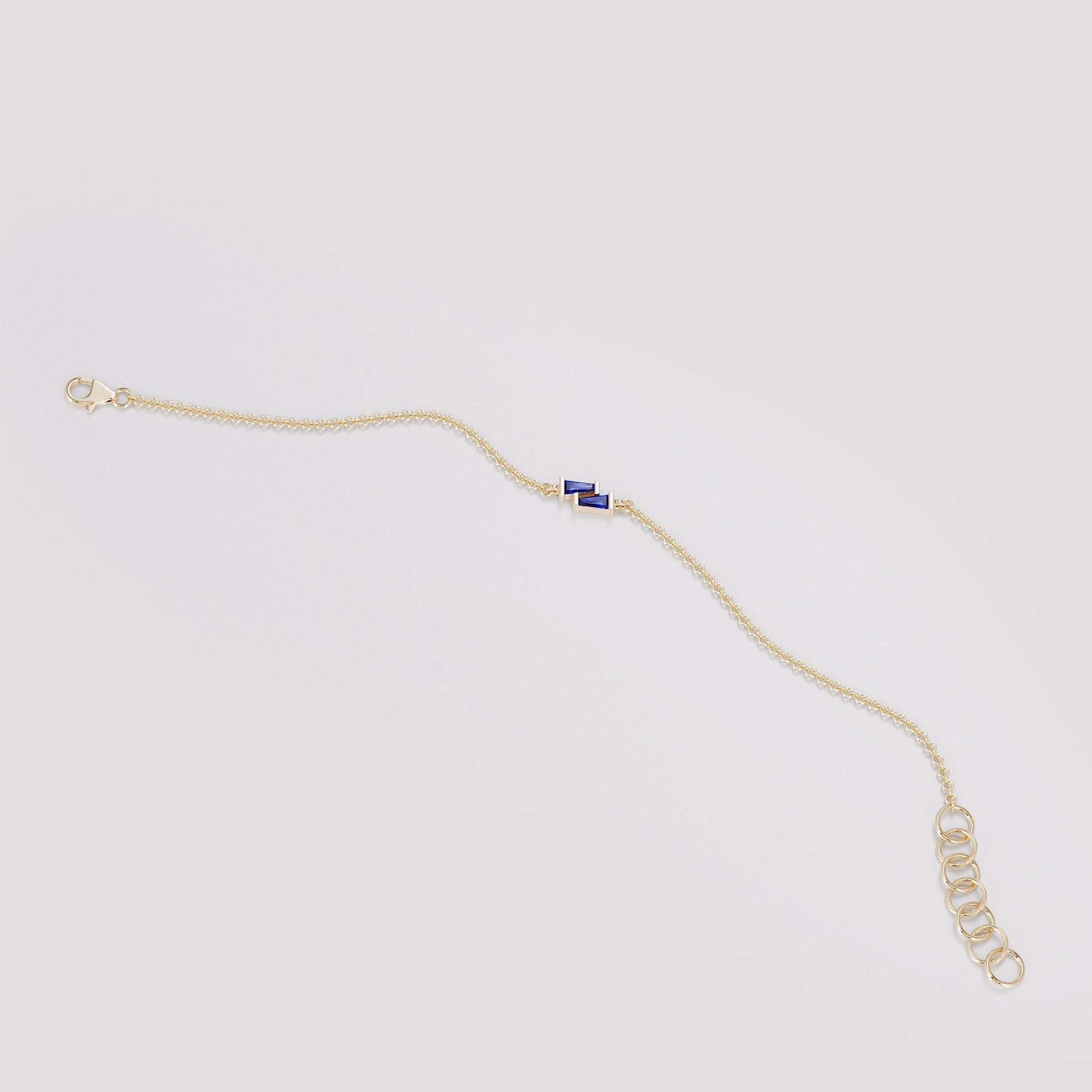 Dainty gold rolo chain bracelet with a blue sapphire baguette charm
