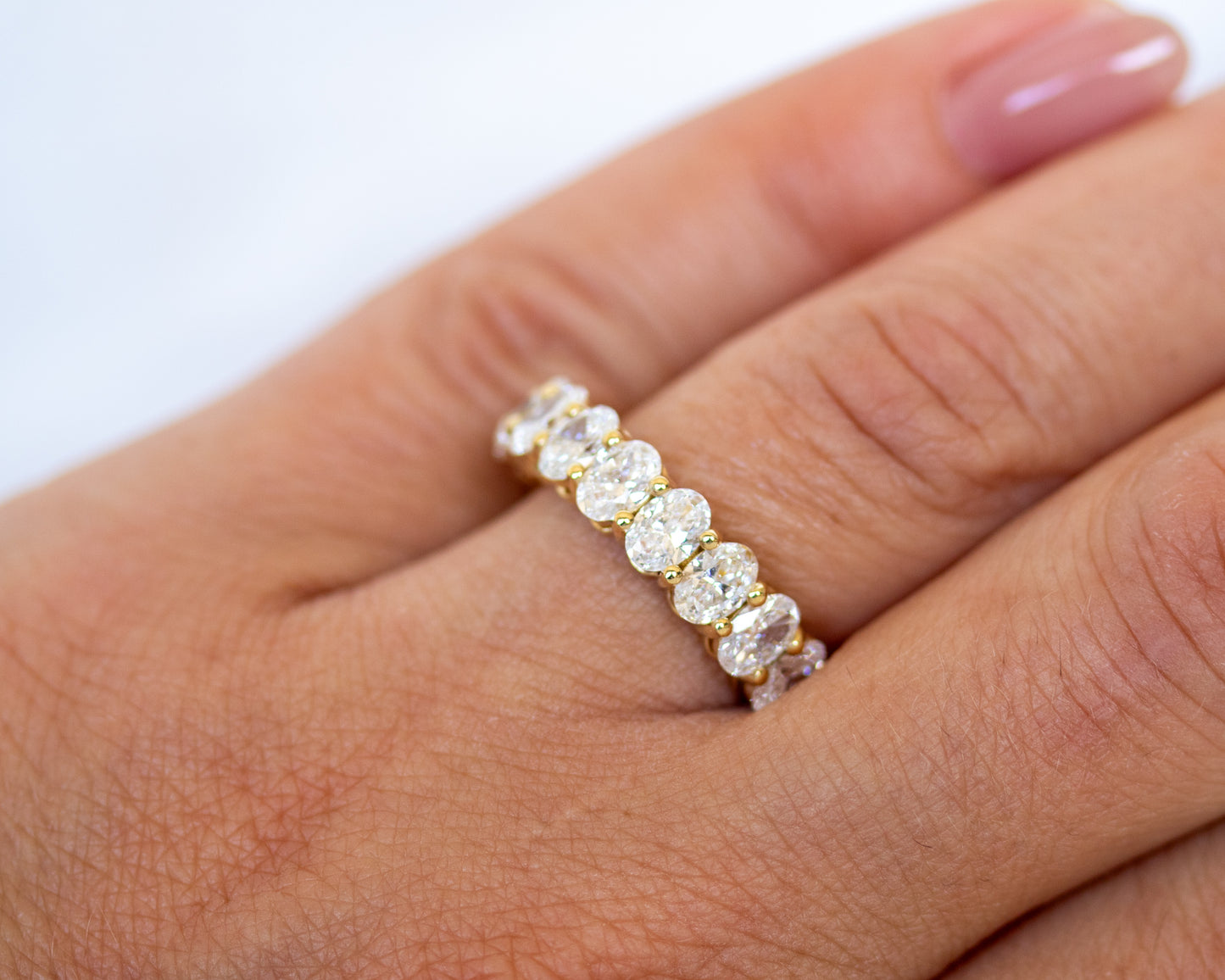 Oval-cut diamond eternity band worn on finger, close-up view