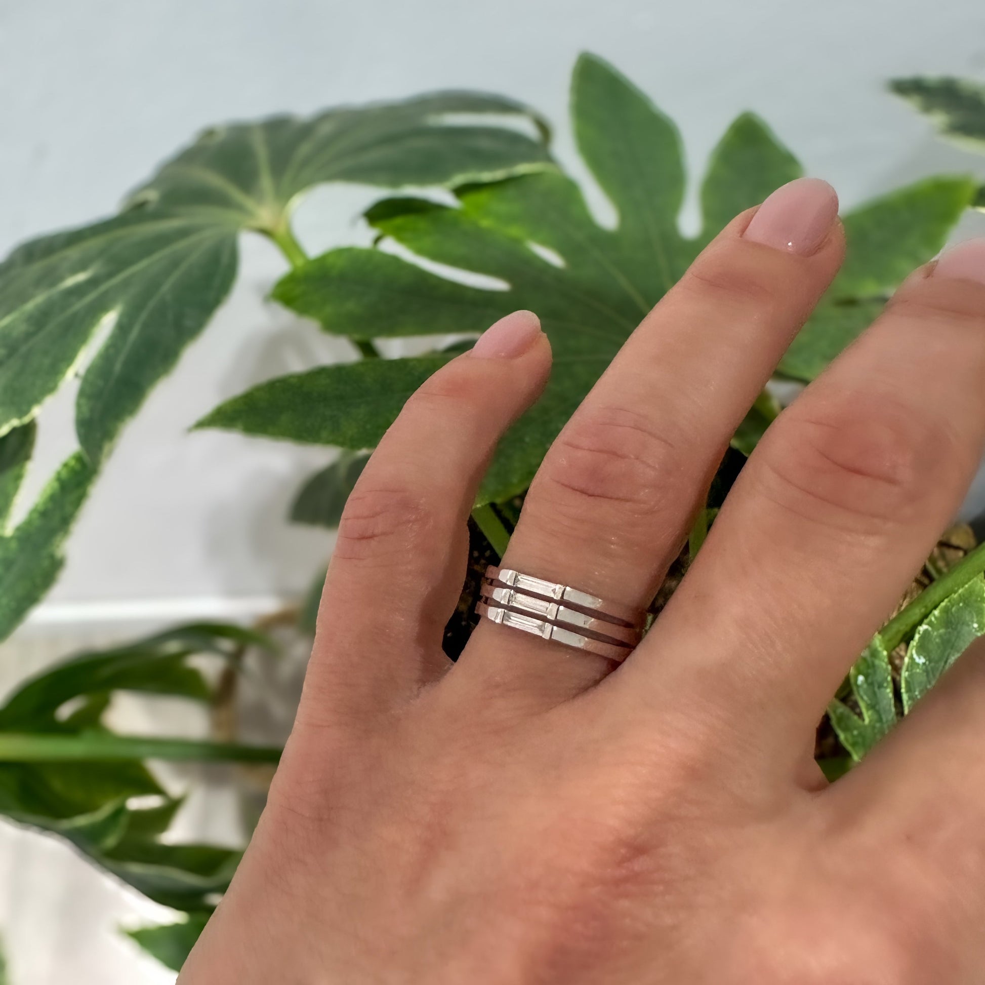 A minimalist ring design with a stack of needle baguette cut sapphires, set in a 14K gold band, on women's hand